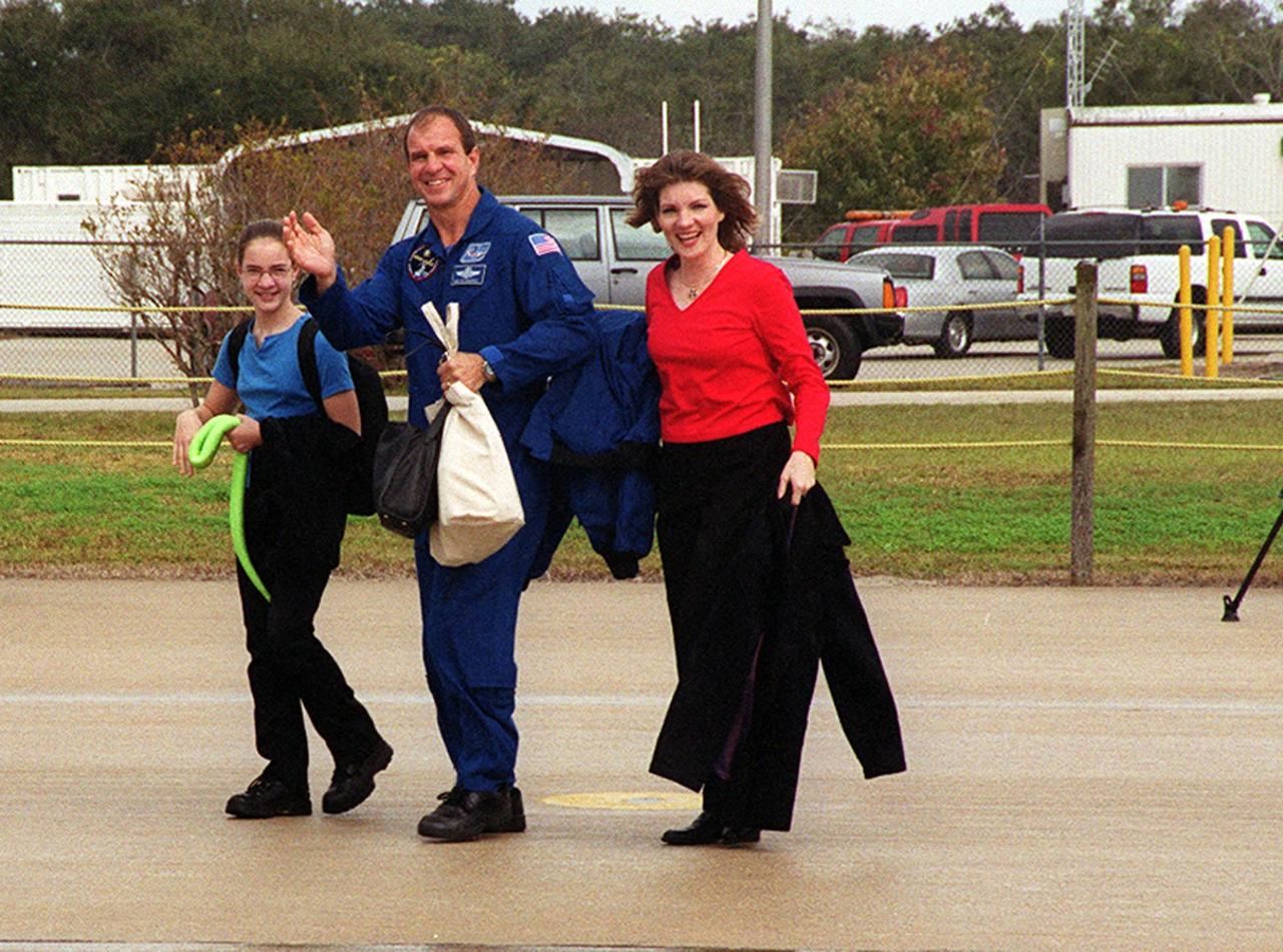 KENNEDY SPACE CENTER, FLA. -- After a night’s rest and a brief press conference at KSC, STS-97 Pilot Michael Bloomfield heads for the plane at the Shuttle Landing Facility. With him are his wife (right) and daughter (left). They and other crew members and their families are returning to Houston. Mission STS-97 ended on Dec. 11, 2000, with a landing at KSC at 6:04 p.m. EST