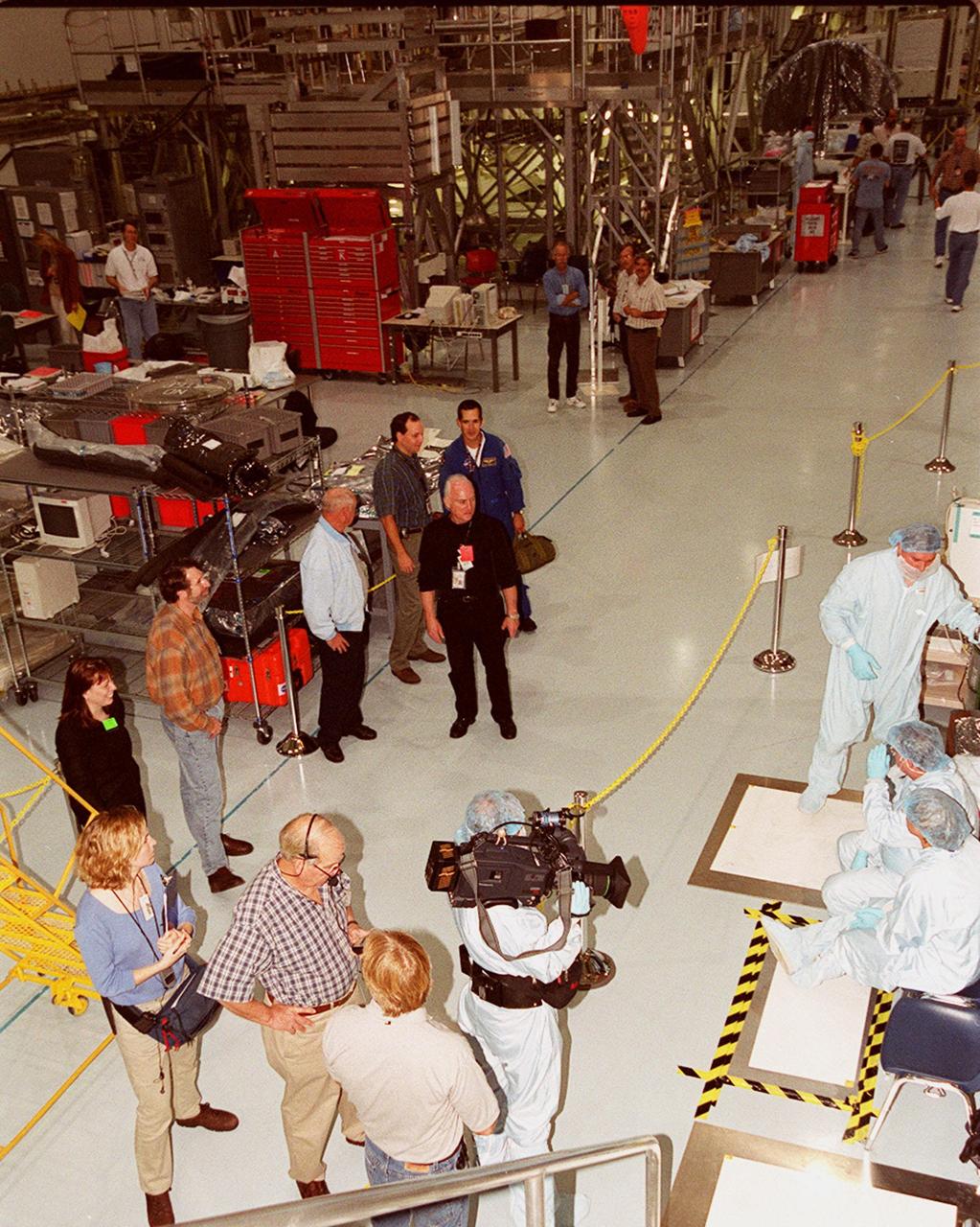 KENNEDY SPACE CENTER, FLA. -- Master Carpenter Norm Abram and crew of the television series "This Old House" stop in the Space Station Processing Facility on their tour of KSC. Abram is at left center. Escorting them is Bill Johnson (center, in the aisle), NASA TV manager; accompanying them is astronaut John Herrington (behind Johnson). Abram is at KSC to film an episode of the series