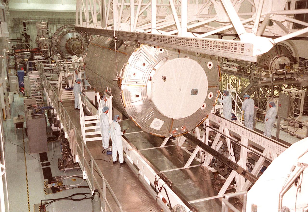 KENNEDY SPACE CENTER, FLA. -- In the Space Station Processing Facility, workers watch while the U.S. Lab Destiny is lowered onto the Launch Package Integration Stand (LPIS) for a weight and center of gravity determination. Destiny is the payload aboard Space Shuttle Atlantis on mission STS-98 to the Space Station. The lab is fitted with five system racks and will already have experiments installed inside for the flight. The launch is scheduled for January 2001