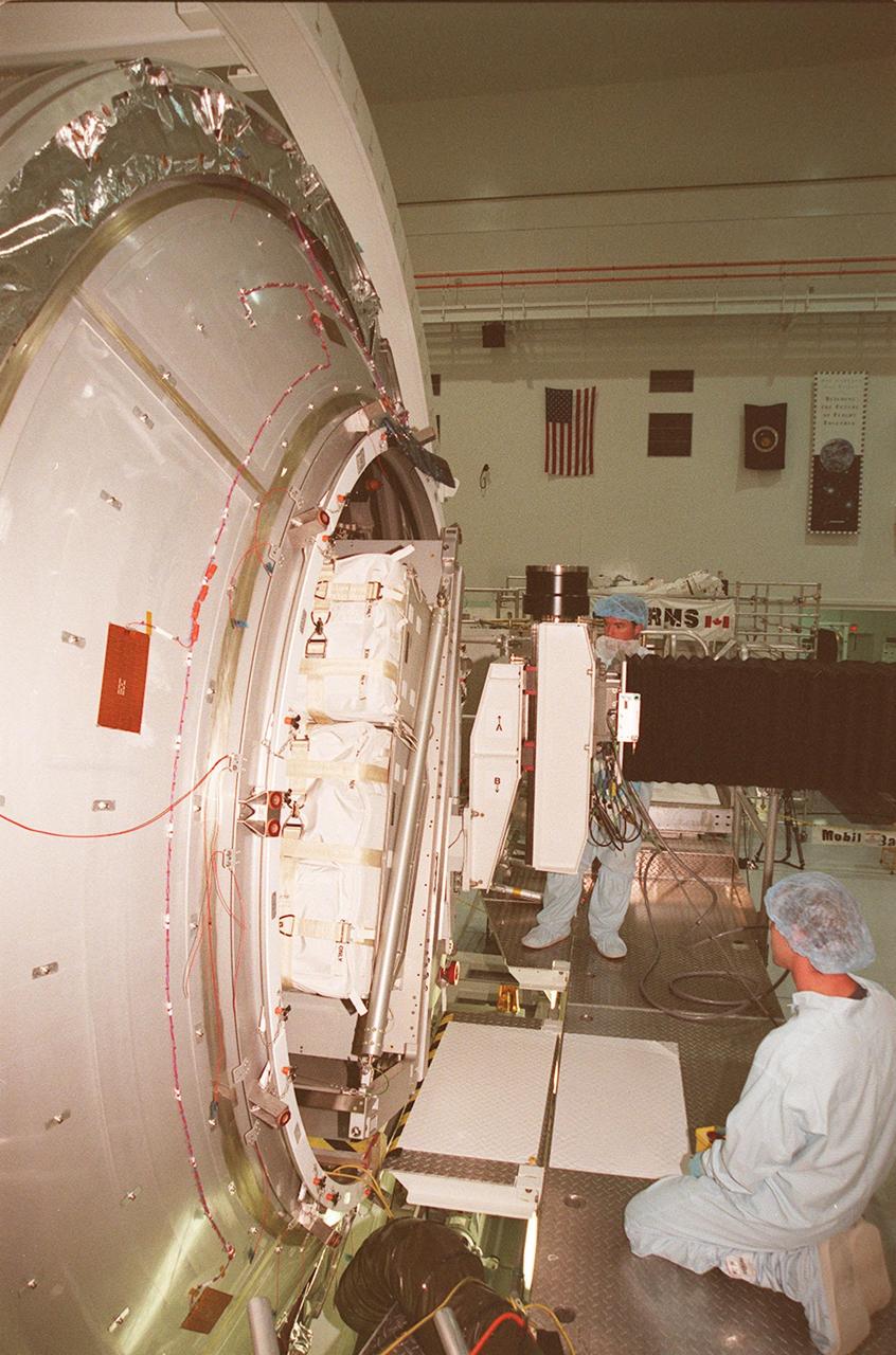 KENNEDY SPACE CENTER, FLA. -- Workers in the Space Station Processing Facility watch as a laboratory rack moves into the Multi-Purpose Logistics Module Leonardo. The MPLM is the first of three such pressurized modules that will serve as the International Space Station’s “moving vans,” carrying laboratory racks filled with equipment, experiments and supplies to and from the Space Station aboard the Space Shuttle. Leonardo will be launched March 1, 2001, on Shuttle mission STS-102 On that flight, Leonardo will be filled with equipment and supplies to outfit the U.S. laboratory module, being carried to the ISS on the Jan. 19, 2001, launch of STS-98
