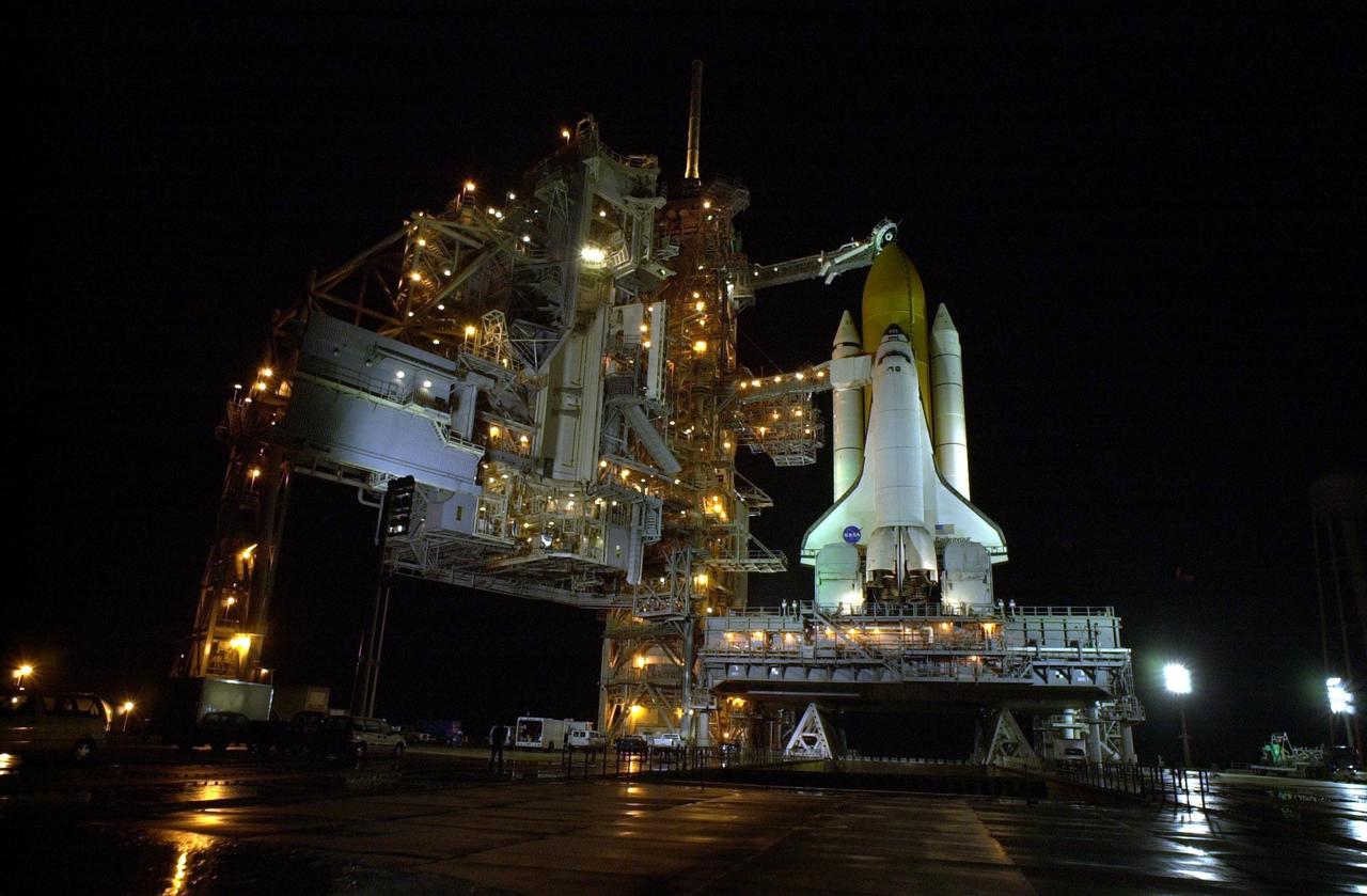 KENNEDY SPACE CENTER, Fla. --   Rain on the ground around Space Shuttle Endeavour on Launch Pad 39B reflects the many lights illluminating the Rotating Service Structure (at left), Fixed Service Structure and Shuttle. Twin solid rocket boosters flank the orange external tank behind Endeavour.  Above the external tank is the Gaseous Oxygen Vent Arm that vents gaseous oxygen vapors away from the Shuttle.  The vent hood assembly at the end is often referred to as the "beanie cap."  Stretching from the FSS to the crew hatch on the side of Endeavour is the Orbiter Access Arm with its environmentally controlled White Room at the end, through which the crew enters the vehicle.  The Shuttle sits on the Mobile Launcher Platform with the two service tail masts on either side of the main engines.  The tail masts support the fluid, gas and electrical requirements of the orbiter's liquid oxygen and liquid hydrogen aft T-0 umbilicals.  Each tail mast is 31 feet (9.4 meters) high, 15 feet (4.6 meters) long and 9 feet (3.1 meters) wide.  Endeavour is scheduled to launch on mission STS-108 Dec. 4 at 5:45  p.m. EST.  On this 12th flight to the International Space Station, known as a Utilization Flight, Endeavour will carry a crew of four plus the Expedition 4 crew, who will replace Expedition 3 aboard the ISS.  The payload includes the Multi-Purpose Logistics Module Raffaello, filled with supplies, equipment and experiments