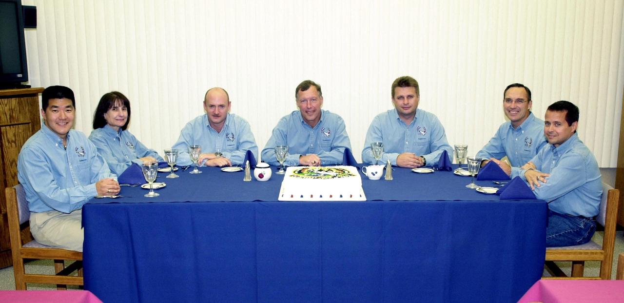 KENNEDY SPACE CENTER, Fla. - The STS-108 and Expedition 4 crews enjoy a traditional pre-launch meal, complete with a cake decorated with the Mission Patch.  Seated from left to right are STS-108 Mission Specialists Daniel M. Tani and Linda A. Godwin, Pilot Mark E. Kelly and Commander Dominic L. Gorie; the Expedition 4 crew Commander Yuri Onufrienko and astronauts Carl E. Walz and Daniel W. Bursch. Top priorities for the STS-108 (UF-1) mission of Endeavour are rotation of the International Space Station Expedition 3 and Expedition 4 crews; bringing water, equipment and supplies to the station in the Multi-Purpose Logistics Module Raffaello; and the crew's completion of robotics tasks and a spacewalk to install thermal blankets over two pieces of equipment at the bases of the Space Station's solar wings.   Launch is scheduled for 5:45 p.m. EST Dec. 4, 2001, from Launch Pad 39B