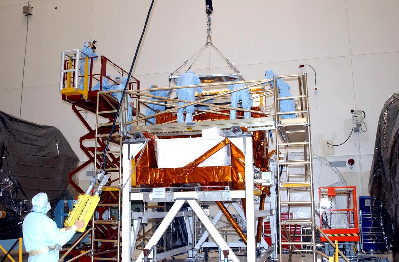 KENNEDY SPACE CENTER, FLA. -- In the Vertical Processing Facility, workers watch while an overhead crane lowers the Advanced Camera for Surveys (ACS) into the Axial Science Instrument Protective Enclosure (ASIPE). The ACS is part of the payload on the Hubble Space Telescope Servicing Mission, STS-109. The goal of the mission is to service the HST, replacing Solar Array 2 with Solar Array 3, replacing the Power Control Unit, removing the Faint Object Camera and installing the ACS, installing the Near Infrared Camera and Multi-Object Spectrometer (NICMOS) Cooling System, and installing New Outer Blanket Layer insulation. Mission STS-109 is scheduled for launch no earlier than Feb. 21, 2002