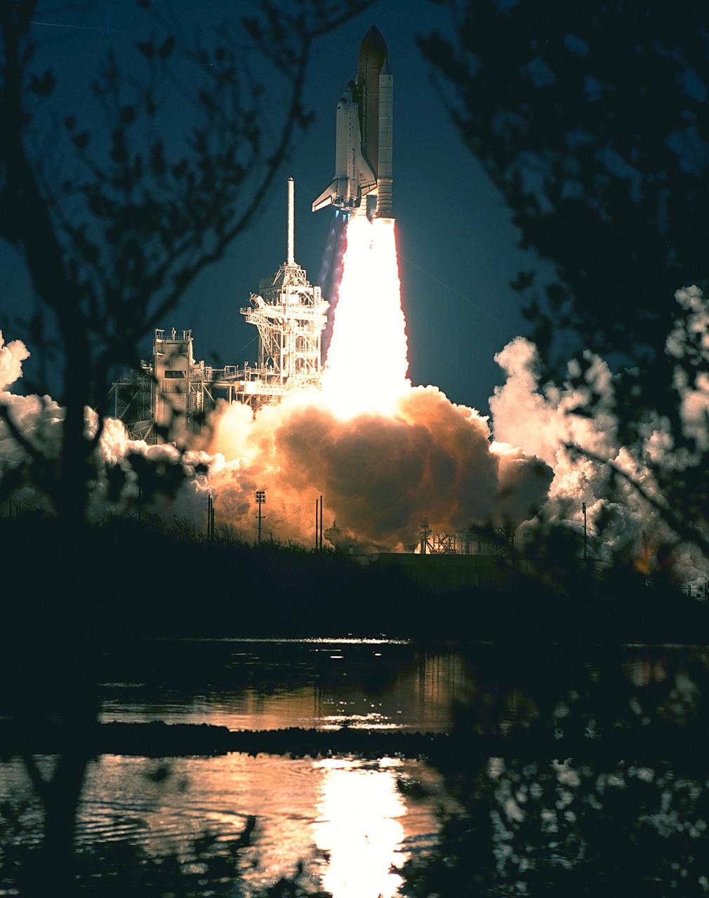 KENNEDY SPACE CENTER, FLA. -- Tree branches across the water from Launch Pad 39A provide a frame for the launch of Space Shuttle Atlantis on mission STS-98. Liftoff occurred at 6:13:02 p.m. EST. Along with a crew of five, Atlantis is carrying the U.S. Laboratory Destiny, a key module in the growth of the Space Station. Destiny will be attached to the Unity node on the Space Station using the Shuttle's robotic arm. Three spacewalks are required to complete the planned construction work during the 11-day mission. This mission marks the seventh Shuttle flight to the Space Station, the 23rd flight of Atlantis and the 102nd flight overall in NASA's Space Shuttle program. The planned landing is at KSC Feb. 18 about 1 p.m. EST