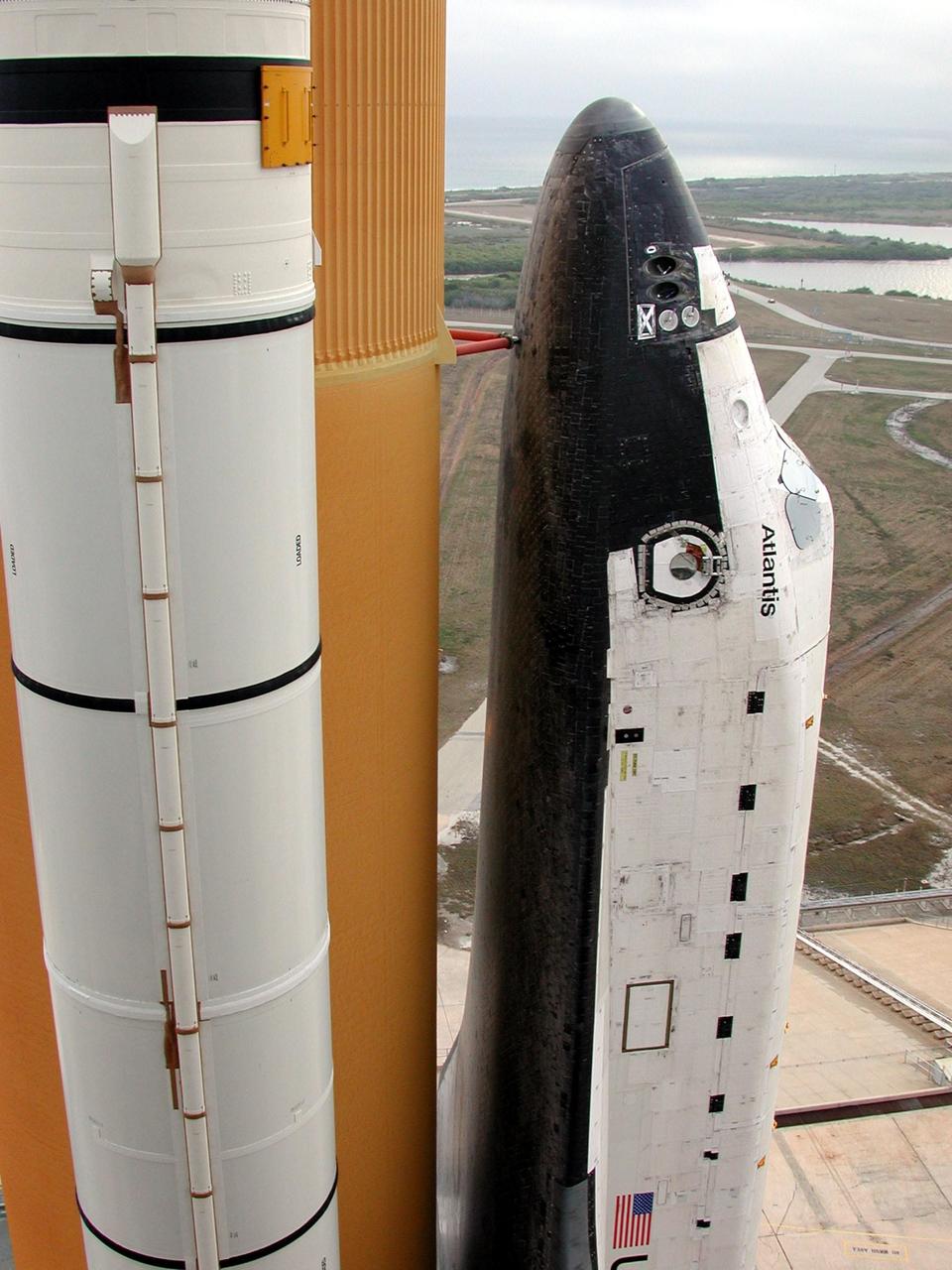 KENNEDY SPACE CENTER, FLA. -- Space Shuttle Atlantis , with its orange external tank and white solid rocket boosters attached, is viewed from the 235-foot level of the Fixed Service Structure on Launch Pad 39A. Atlantis is rolling back to the Vehicle Assembly Building so that workers can conduct inspections, make continuity checks and conduct X-ray analysis on the 36 SRB cables located inside each booster’s system tunnel (seen at left on the outside of the SRB). An extensive evaluation of NASA’s SRB cable inventory revealed conductor damage in four (of about 200) cables on the shelf. Shuttle managers decided to prove the integrity of the system tunnel cables already on Atlantis before launching Jan. 19. The launch has been rescheduled no earlier than Feb. 6