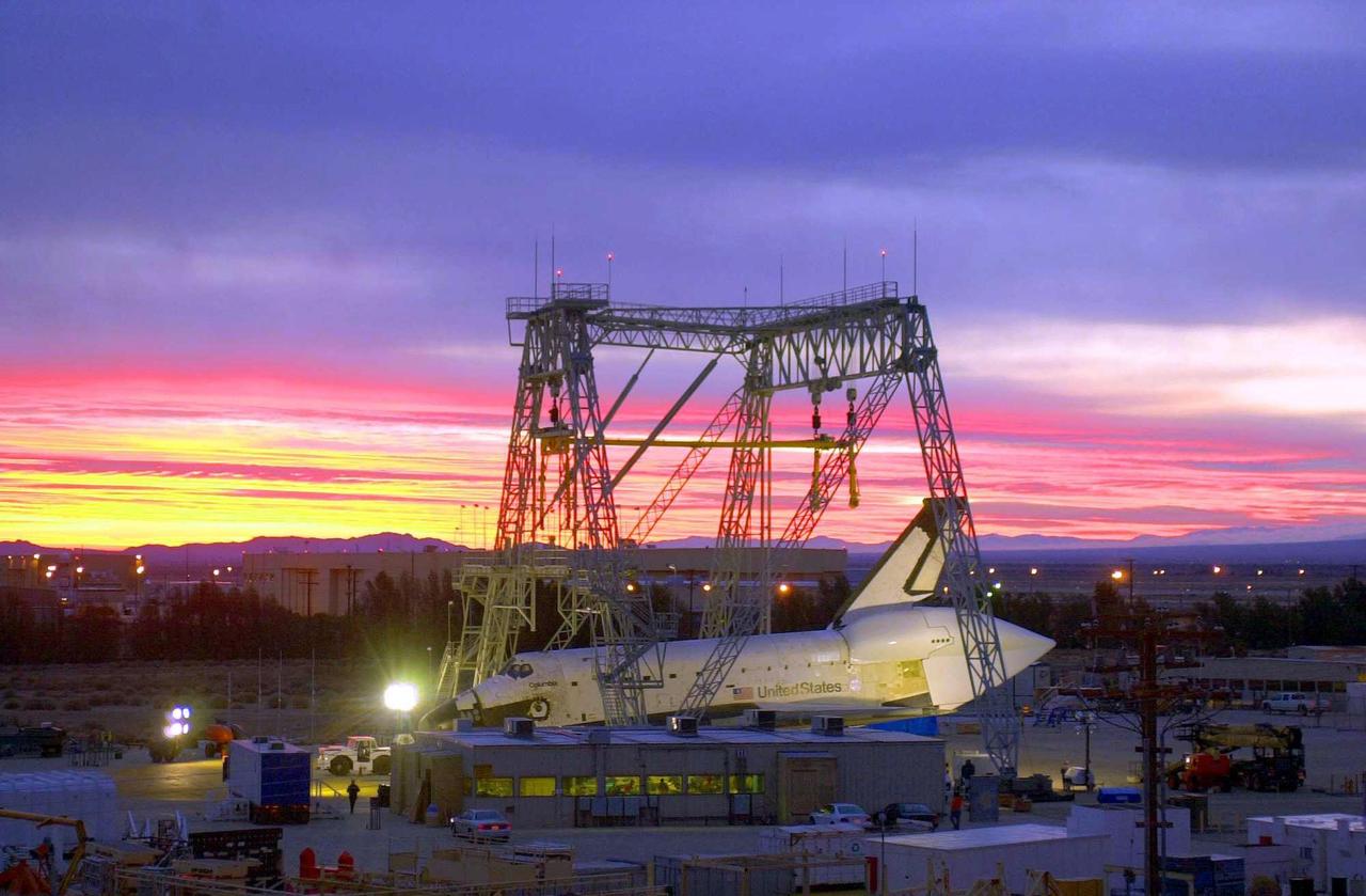 <i>[Photo courtesy of Boeing photographer Bob Williams.]</i> The orbiter Columbia sits under a mate/demate device at Boeing’s Orbiter Assembly Facility in Palmdale, Calif. It is waiting to be mated to Shuttle Carrier Aircraft no. 905 for its ferry flight to Kennedy Space Center. Columbia has been undergoing modifications and upgrades at the Boeing plant. Ferry preparations and the flight plan are contingent upon weather conditions in California and enroute to Florida