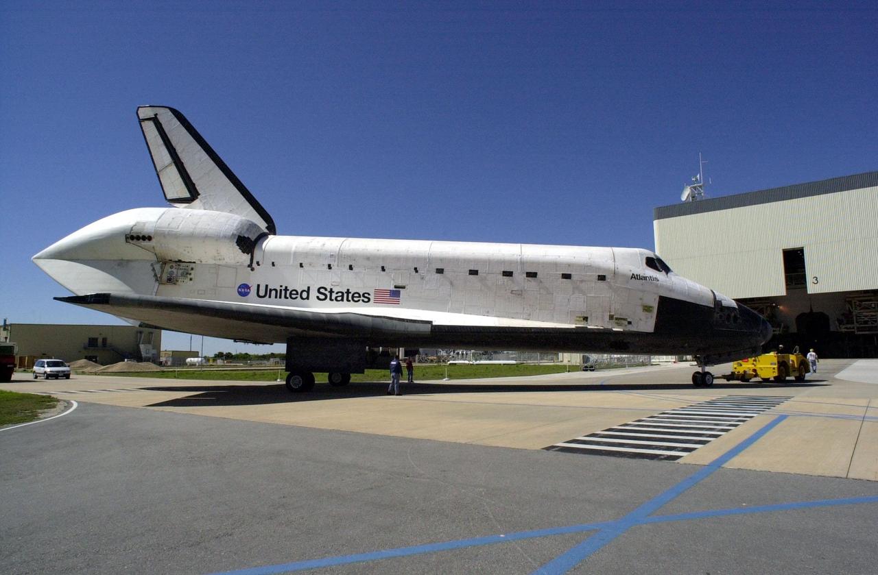 The orbiter Atlantis makes the turn to the Orbiter Processing Facility bay 3 after being towed from the Shuttle Landing Facility. The unusual silhouette of the aft section on the orbiter is due to the tail cone covering the aft engines. Atlantis landed Feb. 19 at Edwards Air Force Base concluding mission STS-98. The orbiter returned to Florida on the back of a Shuttle Carrier Aircraft, known as a ferry flight, that began March 1. Unfavorable weather conditions kept it on the ground at Altus AFB, Okla., for several days until it could return to Florida. Atlantis will be prepared in the OPF for mission STS-104, the 10th construction flight to the International Space Station, scheduled to launch June 8