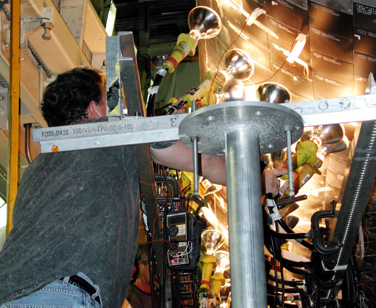 KENNEDY SPACE CENTER, FLA. -- Banks of lights dry tiles on orbiter Atlantis in the Orbiter Processing Facility. Significant rainstorms during the orbiter’s turnaround for a ferry flight home from Edwards Air Force Base, Calif., caused the moisture problem. The tiles are part of the Thermal Protection System used on orbiters for extreme temperatures encountered during landing