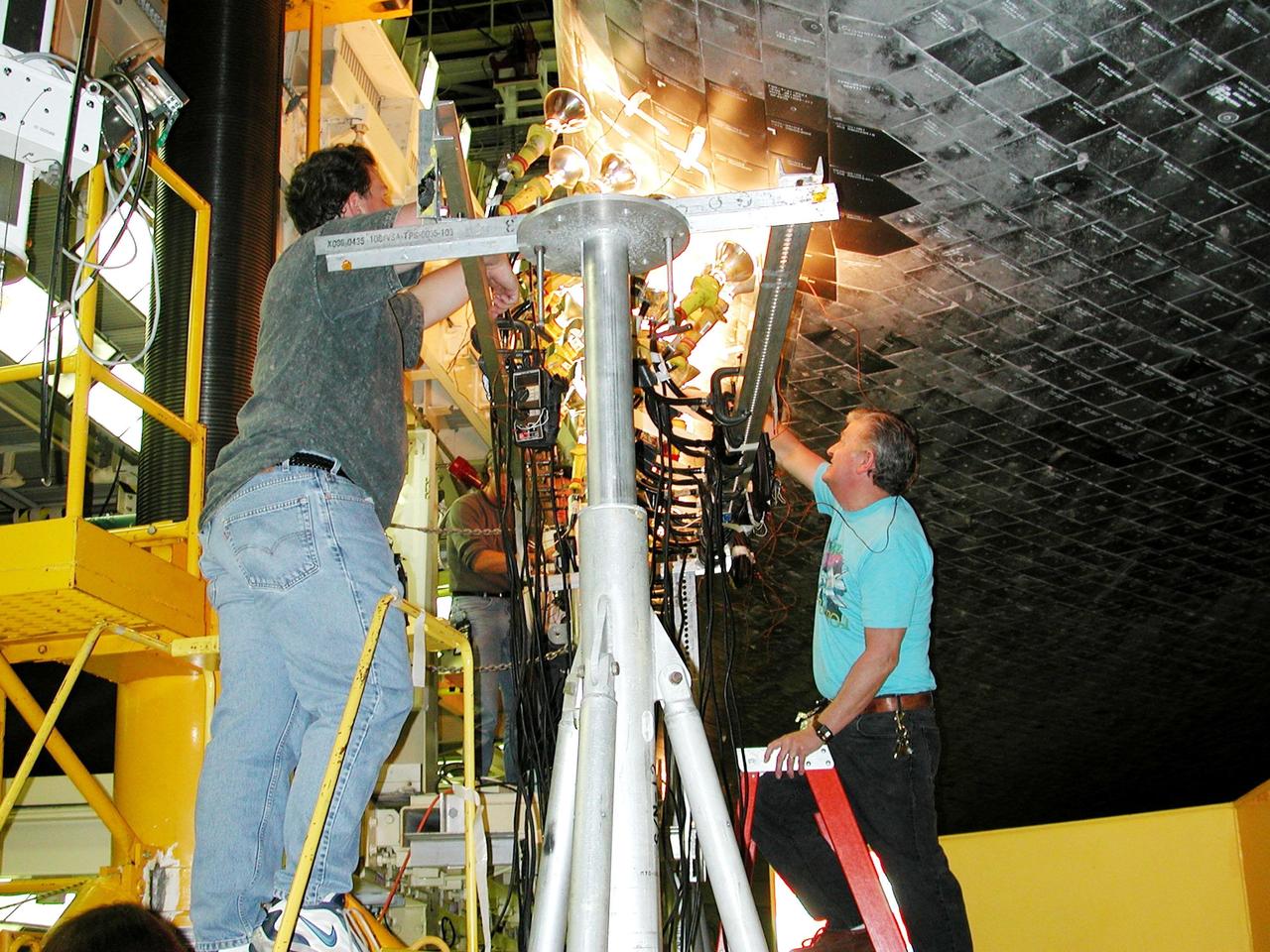 KENNEDY SPACE CENTER, FLA. -- Banks of lights dry tiles on orbiter Atlantis in the Orbiter Processing Facility. Significant rainstorms during the orbiter’s turnaround for a ferry flight home from Edwards Air Force Base, Calif., caused the moisture problem. The tiles are part of the Thermal Protection System used on orbiters for extreme temperatures encountered during landing