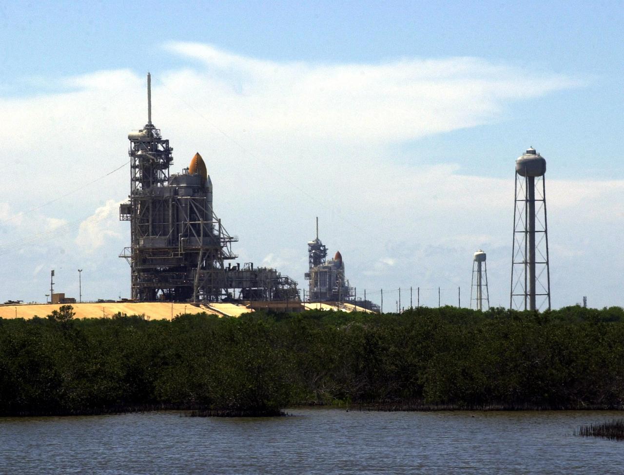 KENNEDY SPACE CENTER, Fla. -- Launch Pads 39A (foreground) and 39B are both seen in this photo, each with a Shuttle in place. Pad 39A holds Space Shuttle Discovery, which rolled out July 2 to be prepared for launch on mission STS-105 in August. Pad 39B holds Space Shuttle Atlantis, which is scheduled to launch Thursday, July 12, on mission STS-104. At right are the 290-foot water tanks that provide 300,000 gallons of water during liftoff. They are part of the sound suppression water system at each pad