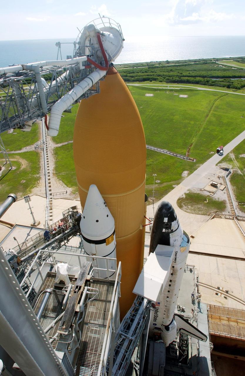 KENNEDY SPACE CENTER, Fla. -- From this high-level view, Space Shuttle Discovery is seen after its rollout to Launch Pad 39A. Extending toward Discovery on the right is the orbiter access arm with the White Room at the end. The White Room provides entry into the orbiter. Above the orange external tank is the gaseous oxygen vent arm with the “beanie cap” hood at the end. Beyond the pad can be seen the Atlantic Ocean. Discovery is scheduled to launch in early August on mission STS-105.     Photo by Scott Andrews using a Nikon D1X camera