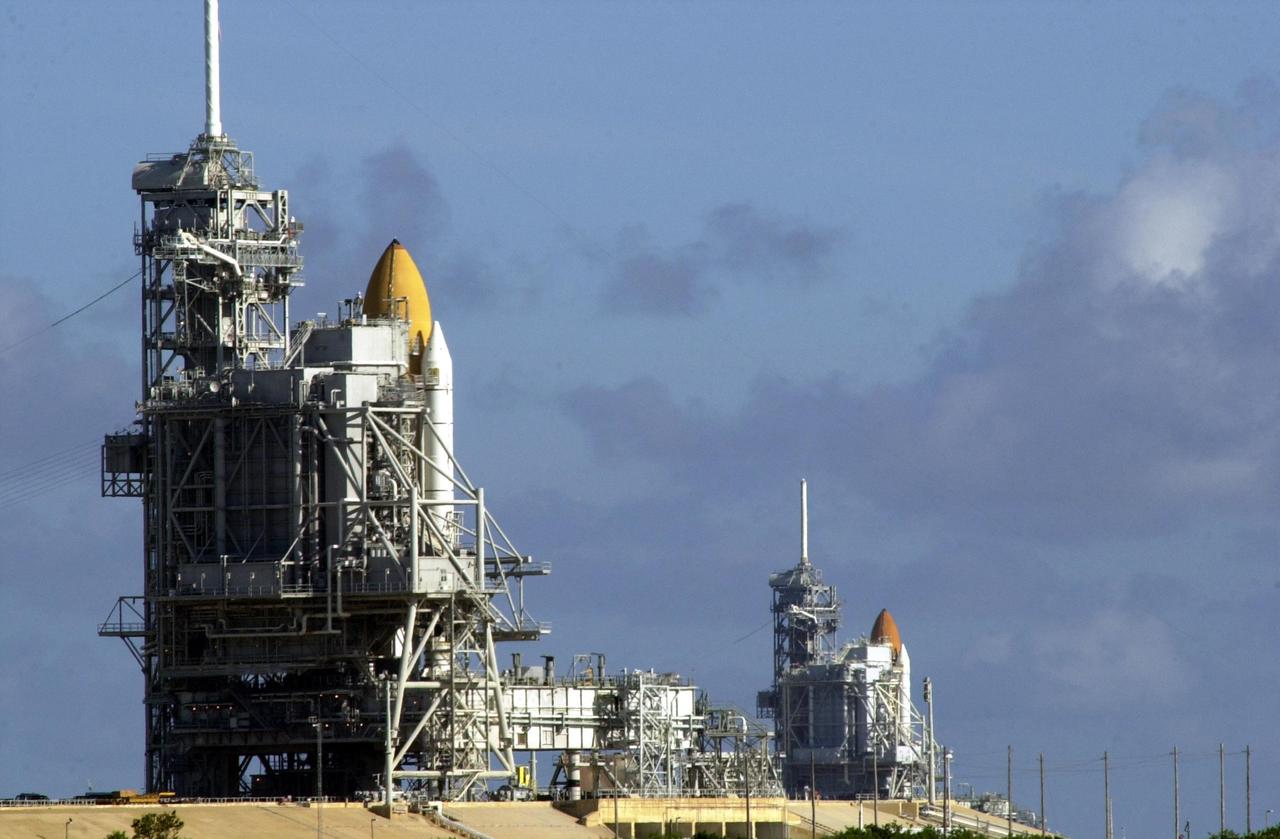 KENNEDY SPACE CENTER, Fla. - Space Shuttle Discovery (foreground) and Space Shuttle Atlantis (background) both stand ready on their Launch Pads ( 39A and 39B respectively). Space Shuttle Discovery rolled out July 2 to be prepared for launch on mission STS-105 in August. Space Shuttle Atlantis is scheduled to launch Thursday, July 12, on mission STS-104. Towering above each Shuttle on the left is the 80-foot lightning rod that helps protect each Shuttle from lightning strikes