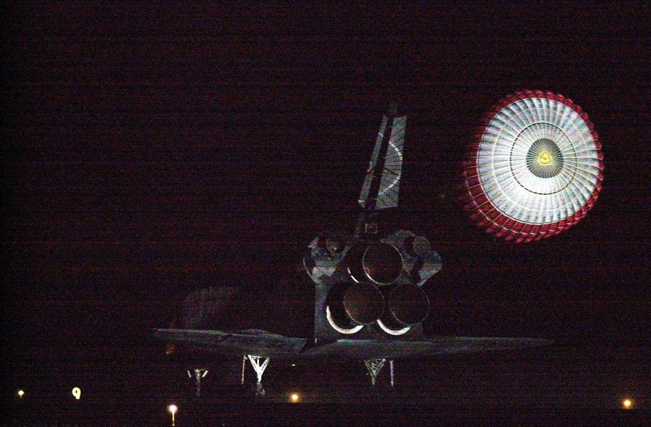 KENNEDY SPACE CENTER, Fla. -- With the drag chute reflected in the bright lights at the Shuttle Landing Facility, Atlantis prepares to land on Runway 15 at the Shuttle Landing Facility to complete a 12-day, 18-hour, 34-minute-long STS-104 mission. Main gear touchdown occurred at 11:38:55 p.m. EDT. At the controls is Commander Steven W. Lindsey. Other crew members on board are Pilot Charles Hobaugh and Mission Specialists Michael Gernhardt, Janet Lynn Kavandi and James F. Reilly. This is the 18th nighttime landing for a Space Shuttle, the 13th at Kennedy Space Center. The mission delivered the Joint Airlock Module to the International Space Station, completing the second phase of the assembly of the Space Station