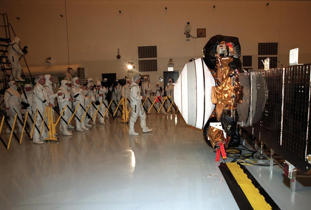 KENNEDY SPACE CENTER, Fla. -- A worker in the Space Assembly and Encapsulation Facility -2 faces the Genesis spacecraft at right as he provides information about it to the media gathered at left. Genesis will capture samples of the ions and elements in the solar wind and return them to Earth for scientists to use to determine the exact composition of the Sun and the solar system's origin. NASA's Genesis project is managed by the Jet Propulsion Laboratory in Pasadena, Calif. Lockheed Martin Astronautics built the Genesis spacecraft for NASA in Denver, Colo. Launch of Genesis aboard a Boeing Delta II rocket is scheduled for July 30 at 12:36 p.m. EDT