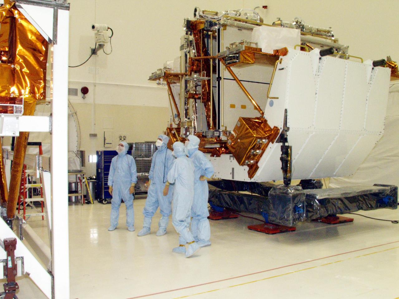 KENNEDY SPACE CENTER, FLA. -- Workers in the Vertical Processing Facility look over the Axial Science Instrument Protective Enclosure (ASIPE), which will house the Advanced Camera for Surveys (ACS), part of the STS-109 flight hardware for maintenance of the Hubble Space Telescope (HST). The Solar Array 3 panels behind them, and other HST hardware, are installed on four principle payload carriers. The STS-109 launch aboard Columbia is targeted for Feb. 14, 2002, and will be the 108th flight in the Space Shuttle program