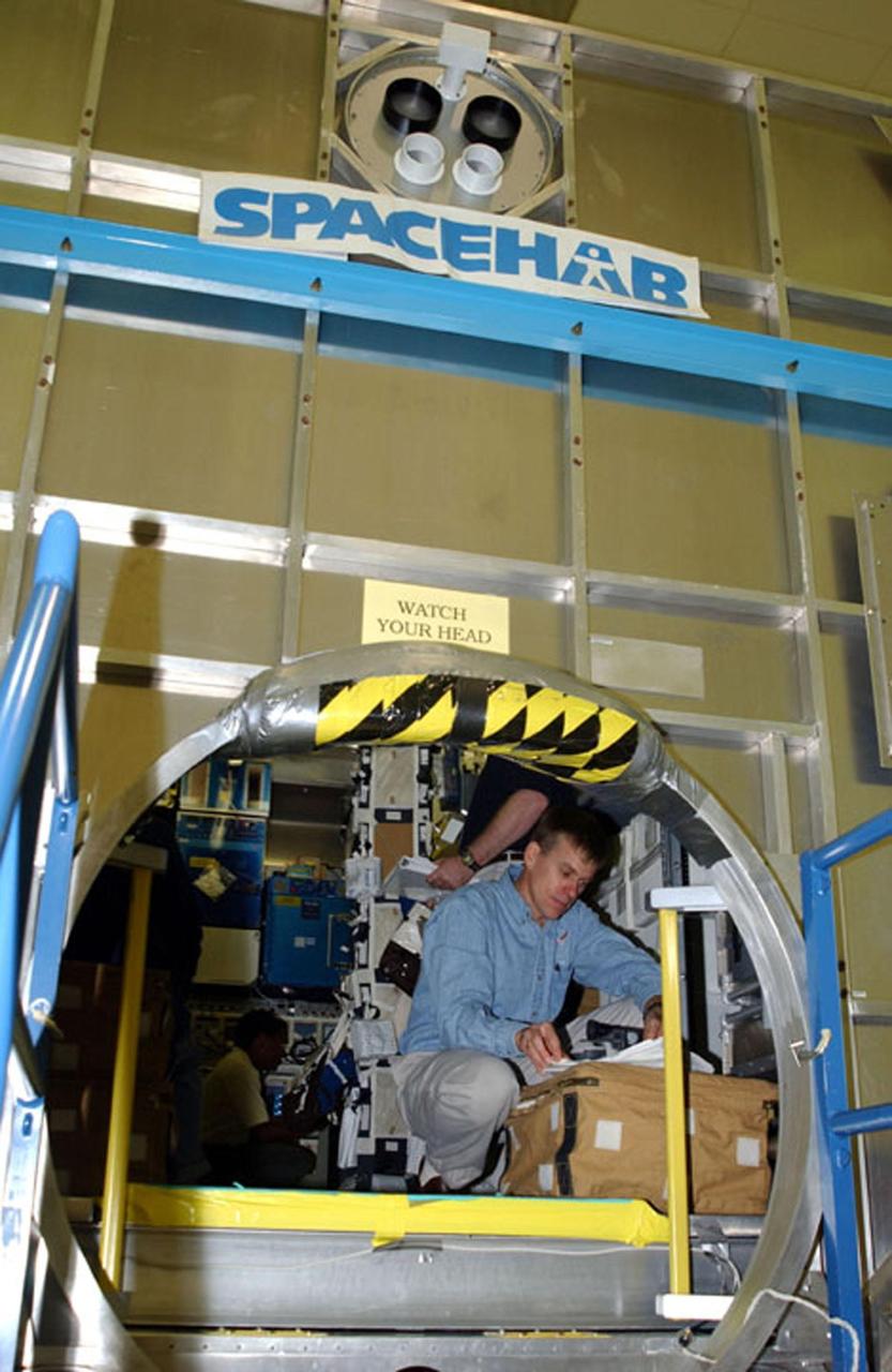 KENNEDY SPACE CENTER, FLA. -  At SPACEHAB, Cape Canaveral, Fla., members of the STS-107 crew look over equipment. Inside the SPACEHAB module, Pilot William "Willie" McCool  scans documents. STS-107 is a research mission, and the primary payload is the first flight of the SHI Research Double Module (SHI/RDM). The experiments range from material sciences to life sciences (many rats).  Among the experiments is a Hitchhiker carrier system, modular and expandable in accordance with payload requirements.  STS-107 is scheduled to launch in June 2002.