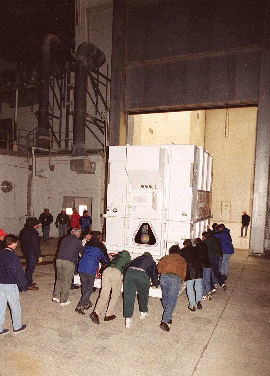 Workers push the crated 2001 Mars Odyssey spacecraft toward the Spacecraft Assembly and Encapsulation Facility 2 (SAEF-2) located in the KSC Industrial Area. The spacecraft arrived at KSC’s Shuttle Landing Facility aboard an Air Force C-17 cargo airplane that brought it from Denver, Colo.., location of the Lockheed Martin plant where the spacecraft was built. In the SAEF, Odyssey will undergo final assembly and checkout. This includes installation of two of the three science instruments, integration of the three-panel solar array, and a spacecraft functional test. It will be fueled and then mated to an upper stage booster, the final activities before going to the launch pad. Launch is planned for April 7, 2001 the first day of a 21-day planetary window. Mars Odyssey will be inserted into an interplanetary trajectory by a Boeing Delta II launch vehicle from Pad A at Complex 17 at the Cape Canaveral Air Force Station, Fla. The spacecraft will arrive at Mars on Oct. 20, 2001, for insertion into an initial elliptical capture orbit. Its final operational altitude will be a 250-mile-high, Sun-synchronous polar orbit. Mars Odyssey will spend two years mapping the planet's surface and measuring its environment