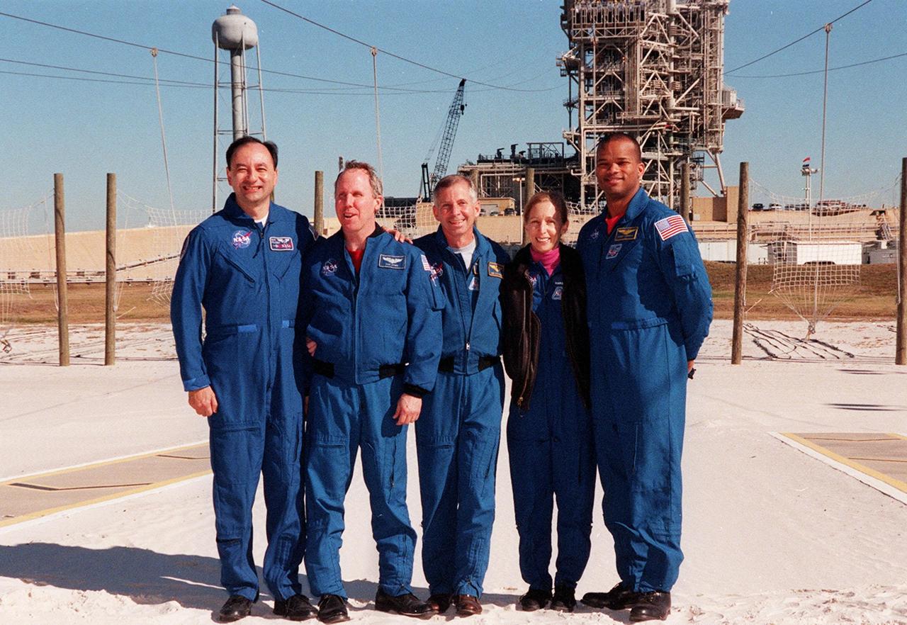 KENNEDY SPACE CENTER, FLA -- After a media briefing at Launch Pad 39A, the STS-98 crew poses in the slidewire basket landing zone. Standing, left to right, are Pilot Mark Polansky, Mission Specialist Thomas Jones, Commander Ken Cockrell and Mission Specialists Marsha Ivins and Robert Curbeam. All are at KSC to take part in Terminal Countdown Demonstration Test activities, which include emergency egress training and a simulated launch countdown. STS-98 is the seventh construction flight to the International Space Station, carrying as payload the U.S. Lab Destiny, a key element in the construction of the ISS. Launch of STS-98 is scheduled for Jan. 19 at 2:11 a.m