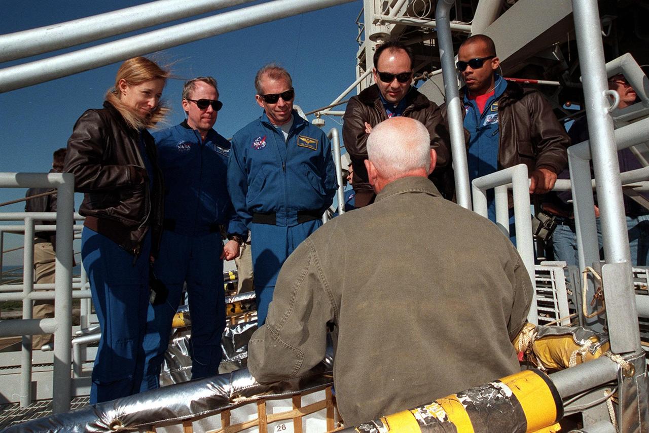 The STS-98 crew listens to instructions on use of the slidewire basket, part of emergency egress equipment from the launch pad. At the 195-foot level of the Fixed Service Structure are Mission Specialists Marsha Ivins and Thomas Jones, Commander Ken Cockrell, Pilot Mark Polansky and Mission Specialist Robert Curbeam. The crew is at KSC to take part in Terminal Countdown Demonstration Test activities, which include emergency egress training and a simulated launch countdown at the pad. STS-98 is the seventh construction flight to the International Space Station, carrying as payload the U.S. Lab Destiny, a key element in the construction of the ISS. Launch of STS-98 is scheduled for Jan. 19 at 2:11 a.m
