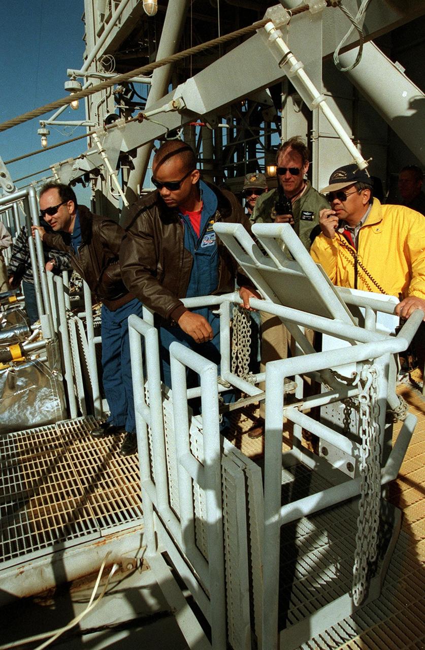At the 195-foot level of the Fixed Service Structure, the STS-98 crew watches a slidewire basket drop to the landing zone. The basket was released by Mission Specialist Robert Curbeam (center); Pilot Mark Polansky is at left. The basket is part of emergency egress equipment from the launch pad. Others (not shown) taking part in the emergency egress training are Commander Ken Cockrell and Mission Specialists Thomas Jones and Marsha Ivins. The crew is at KSC to take part in Terminal Countdown Demonstration Test activities, which include the emergency egress training and a simulated launch countdown at the pad. STS-98 is the seventh construction flight to the International Space Station, carrying as payload the U.S. Lab Destiny, a key element in the construction of the ISS. Launch of STS-98 is scheduled for Jan. 19 at 2:11 a.m