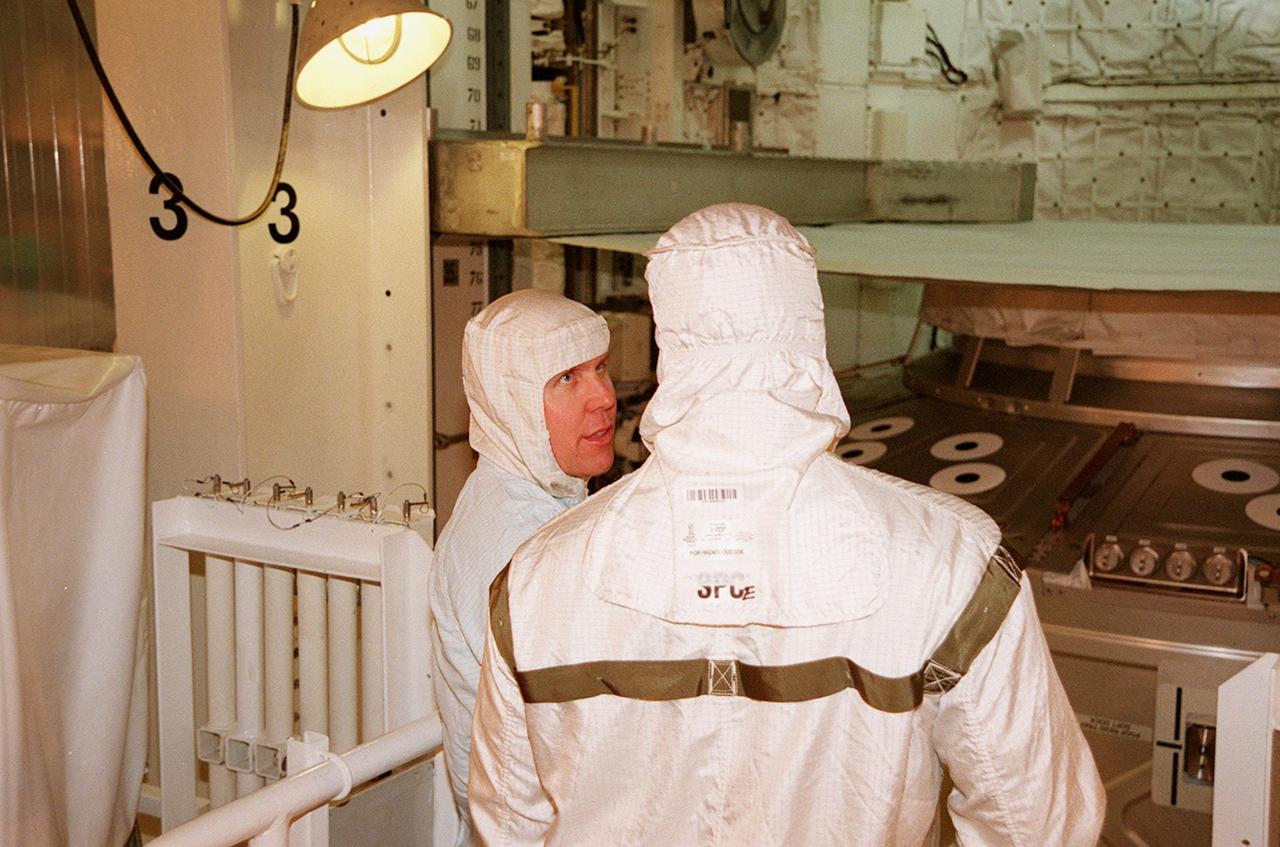KENNEDY SPACE CENTER, FLA. -- In the payload bay of the orbiter Atlantis, STS-98 Mission Specialists Thomas Jones (left) and Robert Curbeam (right) talk about their mission, attaching the U.S. Lab Destiny (in the background) to the International Space Station. The crew is at KSC for Terminal Countdown Demonstration Test activities, which also include a simulated launch countdown. A key element in the construction of the International Space Station, Destiny is a pressurized module designed to accommodate pressurized payloads. It has a capacity of 24 rack locations. Payload racks will occupy 13 locations especially designed to support experiments. The module already has five system racks installed inside. Launch of STS-98 on its 11-day mission is scheduled for Jan. 19 at 2:11 a.m. EST