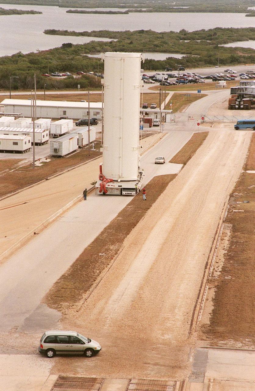 KENNEDY SPACE CENTER, FLA. -- An empty payload canister moves slowly to Launch Pad 39B alongside the crawlerway. In the near background is a crawler-transporter. Across the water, on the horizon can be seen buildings on the launch complexes at Cape Canaveral Air Force Station