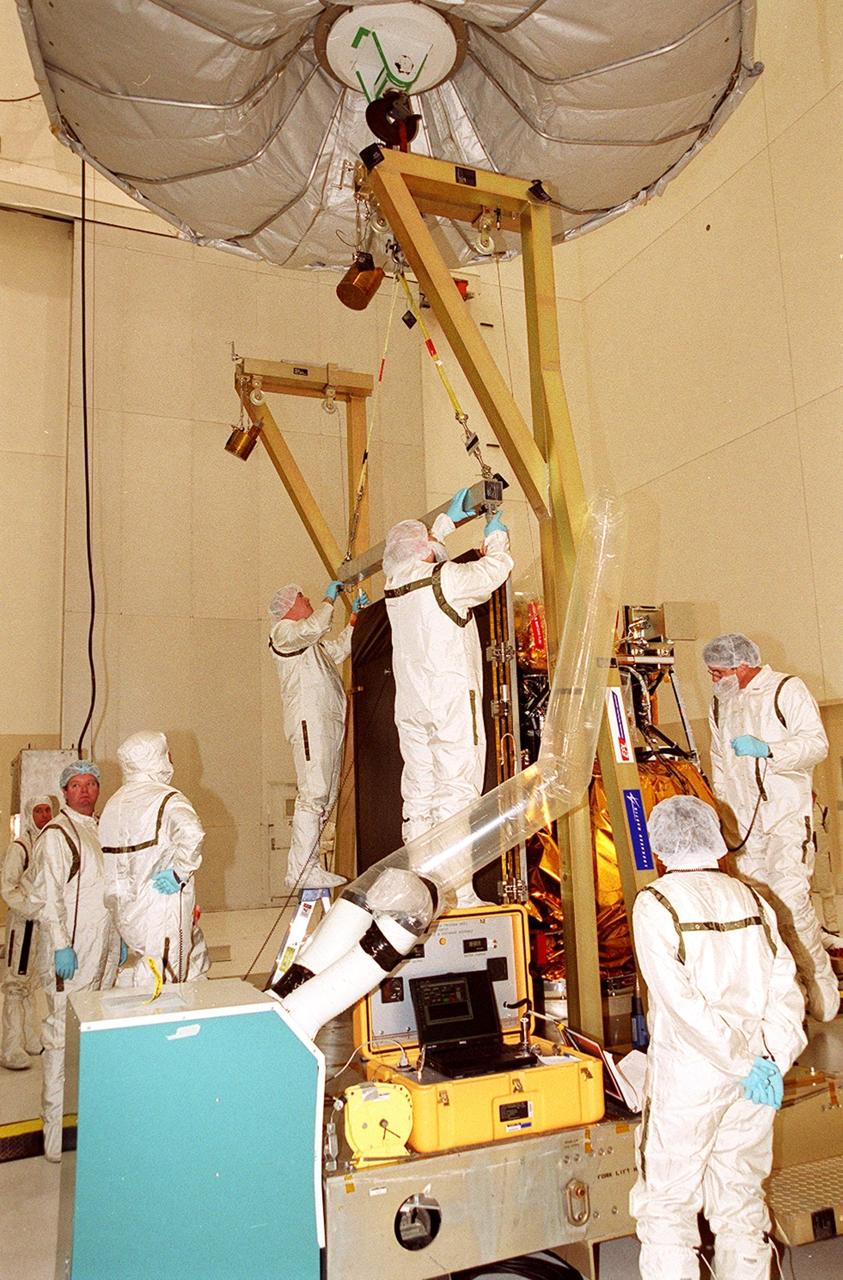 In the Spacecraft Assembly & Encapsulation Facility -2, workers attach an overhead crane to the solar array on the 2001 Mars Odyssey Orbiter to move the component to a workstand. This will give workers access to other components of the spacecraft and allow inspection of the array. The Mars Odyssey carries three science instruments: the Thermal Emission Imaging System (THEMIS), the Gamma Ray Spectrometer (GRS), and the Mars Radiation Environment Experiment (MARIE). THEMIS will map the mineralogy and morphology of the Martian surface using a high-resolution camera and a thermal infrared imaging spectrometer. The GRS will achieve global mapping of the elemental composition of the surface and determine the abundance of hydrogen in the shallow subsurface. [The GRS is a rebuild of the instrument lost with the Mars Observer mission.] The MARIE will characterize aspects of the near-space radiation environment as related to the radiation-related risk to human explorers. The Mars Odyssey Orbiter is scheduled for launch on April 7, 2001, aboard a Delta 7925 rocket from Launch Pad 17-A, Cape Canaveral Air Force Station