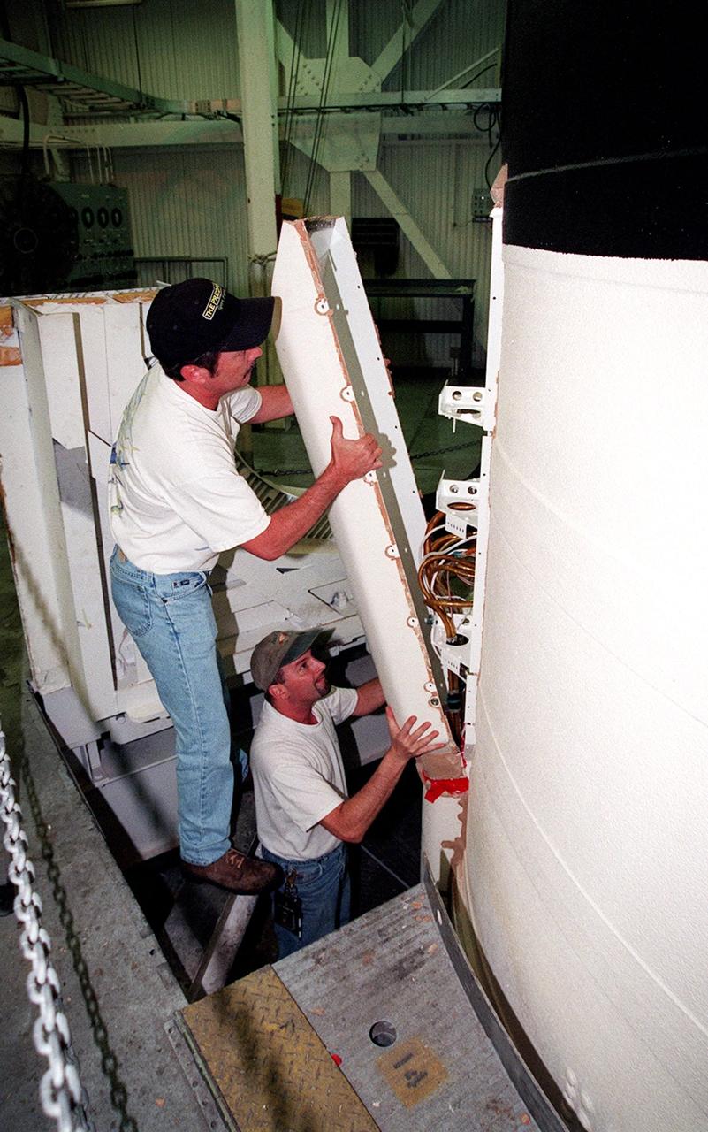KENNEDY SPACE CENTER, FLA. -- In the Vehicle Assembly Building, United Space Alliance SRB technicians Robert G. Williams and Frank Meyer remove the cover of the solid rocket booster system tunnel. The SRB is part of Space Shuttle Atlantis, rolled back from Launch Pad 39A in order to conduct tests on the cables. A prior extensive evaluation of NASA’s SRB cable inventory on the shelf revealed conductor damage in four (of about 200) cables. Shuttle managers decided to prove the integrity of the system tunnel cables already on Atlantis before launching. Workers are conducting inspections, making continuity checks and conducting X-ray analysis on the cables. The launch has been rescheduled no earlier than Feb. 6. <br
