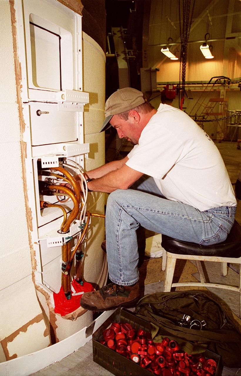 KENNEDY SPACE CENTER, FLA. -- In the Vehicle Assembly Building, United Space Alliance SRB technician Frank Meyer pulls cables out of the solid rocket booster system tunnel. Cable end covers are in a box near his feet. The SRB is part of Space Shuttle Atlantis, rolled back from Launch Pad 39A in order to conduct tests on the cables. A prior extensive evaluation of NASA’s SRB cable inventory on the shelf revealed conductor damage in four (of about 200) cables. Shuttle managers decided to prove the integrity of the system tunnel cables already on Atlantis before launching. Workers are conducting inspections, making continuity checks and conducting X-ray analysis on the cables. The launch has been rescheduled no earlier than Feb. 6. <br