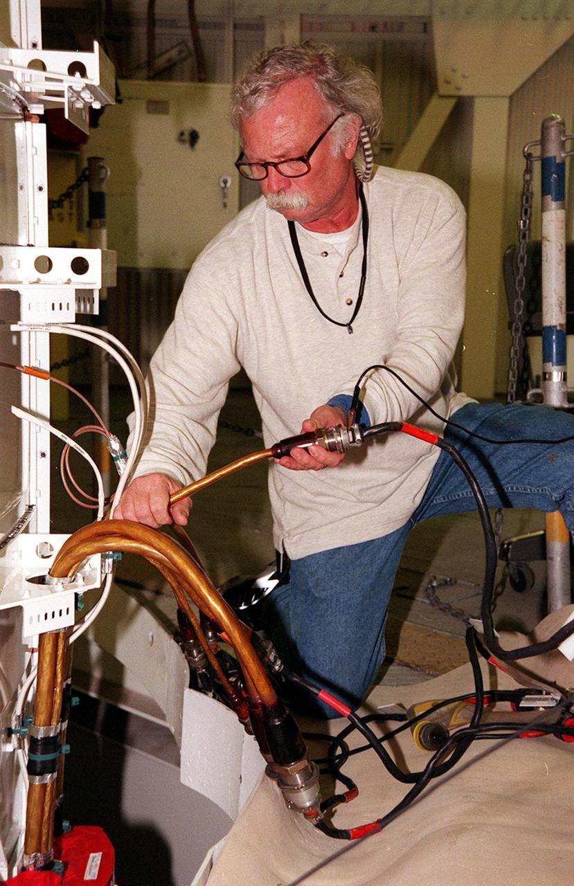 KENNEDY SPACE CENTER, FLA. -- United Space Alliance SRB technician Jim Glass conducts a Flex test on a cable on the solid rocket booster at left. The SRB is part of Space Shuttle Atlantis, rolled back from Launch Pad 39A in order to conduct tests on the cables. A prior extensive evaluation of NASA’s SRB cable inventory on the shelf revealed conductor damage in four (of about 200) cables. Shuttle managers decided to prove the integrity of the system tunnel cables already on Atlantis before launching. Workers are conducting inspections, making continuity checks and conducting X-ray analysis on the cables. The launch has been rescheduled no earlier than Feb. 6. <br