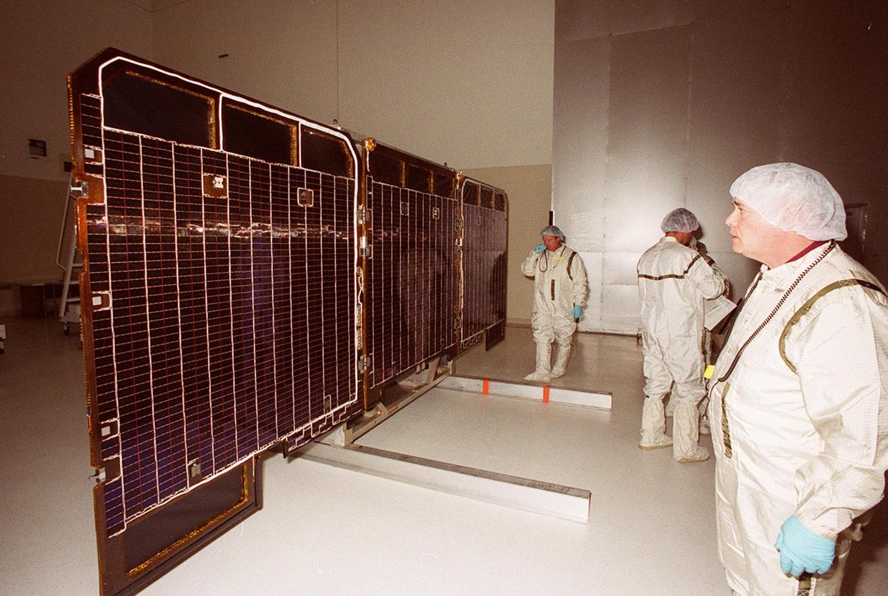 Workers in the Spacecraft Assembly & Encapsulation Facility -2 take a close look at the back side of the opened solar array panels from the 2001 Mars Odyssey Orbiter. The Mars Odyssey carries three science instruments: the Thermal Emission Imaging System (THEMIS), the Gamma Ray Spectrometer (GRS), and the Mars Radiation Environment Experiment (MARIE). THEMIS will map the mineralogy and morphology of the Martian surface using a high-resolution camera and a thermal infrared imaging spectrometer. The GRS will achieve global mapping of the elemental composition of the surface and determine the abundance of hydrogen in the shallow subsurface. [The GRS is a rebuild of the instrument lost with the Mars Observer mission.] The MARIE will characterize aspects of the near-space radiation environment as related to the radiation-related risk to human explorers. The Mars Odyssey Orbiter is scheduled for launch on April 7, 2001, aboard a Delta 7925 rocket from Launch Pad 17-A, Cape Canaveral Air Force Station
