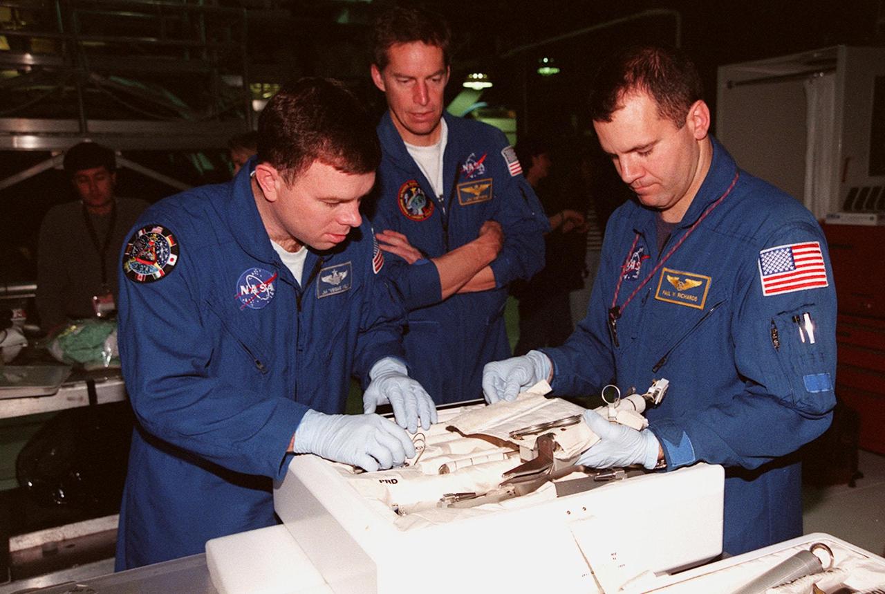STS-102 Pilot James W. Kelly (left) and Mission Specialist Paul W. Richards look over equipment in the tool caddy that is carried on launches. Commander James D. Wetherbee (center) watches. The mission crew is at KSC for Crew Equipment Interface Test activities. STS-102 is the 8th construction flight to the International Space Station and will carry the Multi-Purpose Logistics Module Leonardo. STS-102 is scheduled for launch March 1, 2001. On that flight, Leonardo will be filled with equipment and supplies to outfit the U.S. laboratory module Destiny. The mission will also be carrying the Expedition Two crew to the Space Station, replacing the Expedition One crew who will return on Shuttle Discovery