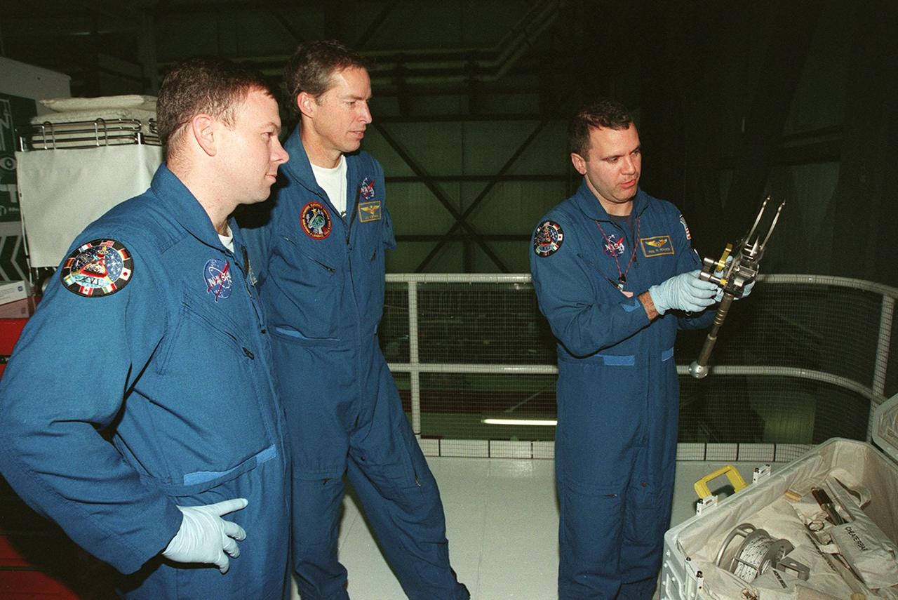 While STS-102 Pilot James W. Kelly and Commander James D. Wetherbee watch, Mission Specialist Paul W. Richards checks out a piece of equipment from the tool caddy below. The mission crew is at KSC for Crew Equipment Interface Test activities. STS-102 is the 8th construction flight to the International Space Station and will carry the Multi-Purpose Logistics Module Leonardo. STS-102 is scheduled for launch March 1, 2001. On that flight, Leonardo will be filled with equipment and supplies to outfit the U.S. laboratory module Destiny. The mission will also be carrying the Expedition Two crew to the Space Station, replacing the Expedition One crew who will return on Shuttle Discovery