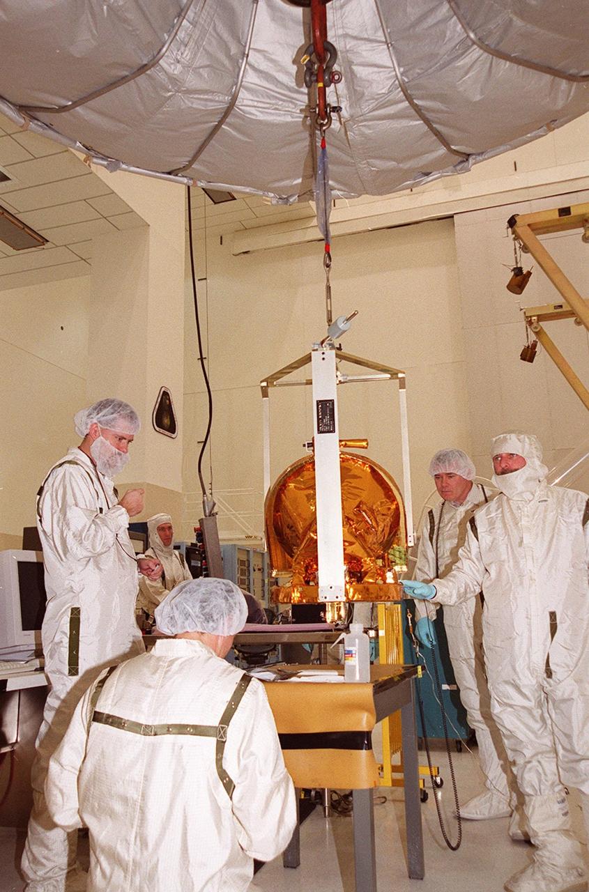 In the Spacecraft Assembly and Encapsulation Facility 2 (SAEF 2), workers attach a crane to the Gamma Ray Spectrometer (GRS); to move it into place to be installed on the Mars Odyssey Orbiter.; The orbiter will carry three science instruments: the Thermal Emission Imaging System (THEMIS), the Gamma Ray Spectrometer (GRS), and the Mars Radiation Environment Experiment (MARIE). THEMIS will map the mineralogy and morphology of the Martian surface using a high-resolution camera and a thermal infrared imaging spectrometer. The GRS will achieve global mapping of the elemental composition of the surface and determine the abundance of hydrogen in the shallow subsurface. [The GRS is a rebuild of the instrument lost with the Mars Observer mission.] The MARIE will characterize aspects of the near-space radiation environment with regards to the radiation-related risk to human explorers. The Mars Odyssey Orbiter is scheduled for launch on April 7, 2001, aboard a Delta 7925 rocket from Launch Pad 17-A, Cape Canaveral Air Force Station