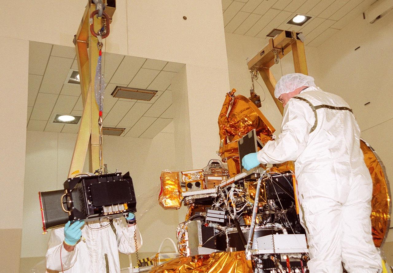 In the Spacecraft Assembly and Encapsulation Facility 2 (SAEF 2), the Thermal Emission Imaging System (THEMIS), left, is moved toward the Mars Odyssey Orbiter, at right. THEMIS will map the mineralogy and morphology of the Martian surface using a high-resolution camera and a thermal infrared imaging spectrometer. The orbiter will carry three science instruments: THEMIS, the Gamma Ray Spectrometer (GRS), and the Mars Radiation Environment Experiment (MARIE). The GRS will achieve global mapping of the elemental composition of the surface and determine the abundance of hydrogen in the shallow subsurface. The MARIE will characterize aspects of the near-space radiation environment with regards to the radiation-related risk to human explorers. The Mars Odyssey Orbiter is scheduled for launch on April 7, 2001, aboard a Delta 7925 rocket from Launch Pad 17-A, Cape Canaveral Air Force Station