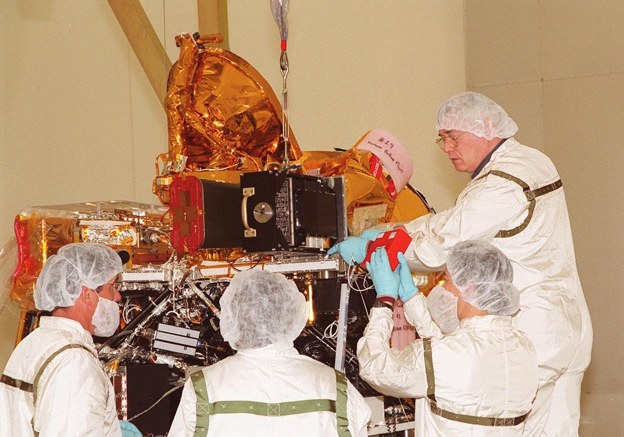 Workers in the Spacecraft Assembly and Encapsulation Facility 2 check the placement of the Thermal Emission Imaging System (THEMIS) on the Mars Odyssey Orbiter. THEMIS will map the mineralogy and morphology of the Martian surface using a high-resolution camera and a thermal infrared imaging spectrometer. The orbiter will carry three science instruments: THEMIS, the Gamma Ray Spectrometer (GRS), and the Mars Radiation Environment Experiment (MARIE). The GRS will achieve global mapping of the elemental composition of the surface and determine the abundance of hydrogen in the shallow subsurface. The MARIE will characterize aspects of the near-space radiation environment with regards to the radiation-related risk to human explorers. The Mars Odyssey Orbiter is scheduled for launch on April 7, 2001, aboard a Delta 7925 rocket from Launch Pad 17-A, Cape Canaveral Air Force Station