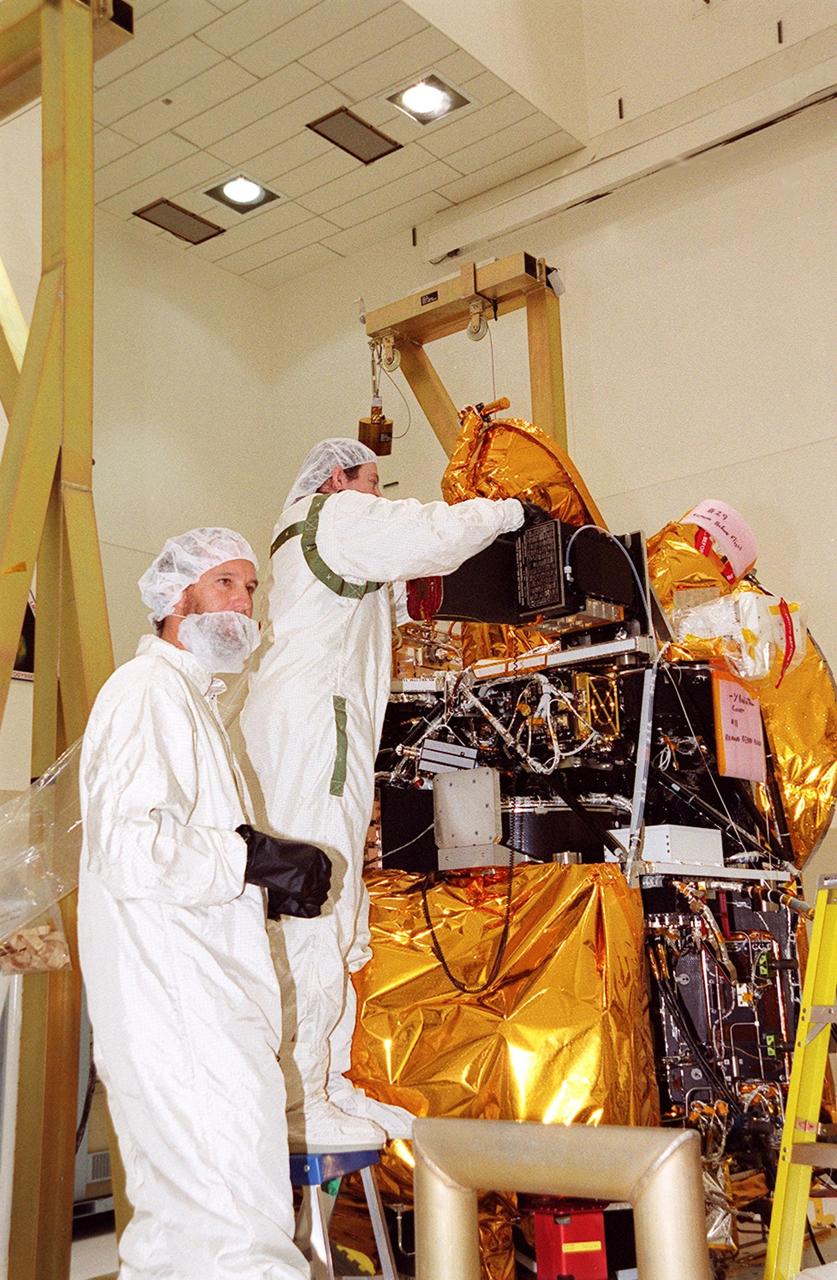 Workers in the Spacecraft Assembly and Encapsulation Facility 2 adjust the placement of the Thermal Emission Imaging System (THEMIS) on the Mars Odyssey Orbiter. THEMIS will map the mineralogy and morphology of the Martian surface using a high-resolution camera and a thermal infrared imaging spectrometer. The orbiter will carry three science instruments: THEMIS, the Gamma Ray Spectrometer (GRS), and the Mars Radiation Environment Experiment (MARIE). The GRS will achieve global mapping of the elemental composition of the surface and determine the abundance of hydrogen in the shallow subsurface. The MARIE will characterize aspects of the near-space radiation environment with regards to the radiation-related risk to human explorers. The Mars Odyssey Orbiter is scheduled for launch on April 7, 2001, aboard a Delta 7925 rocket from Launch Pad 17-A, Cape Canaveral Air Force Station