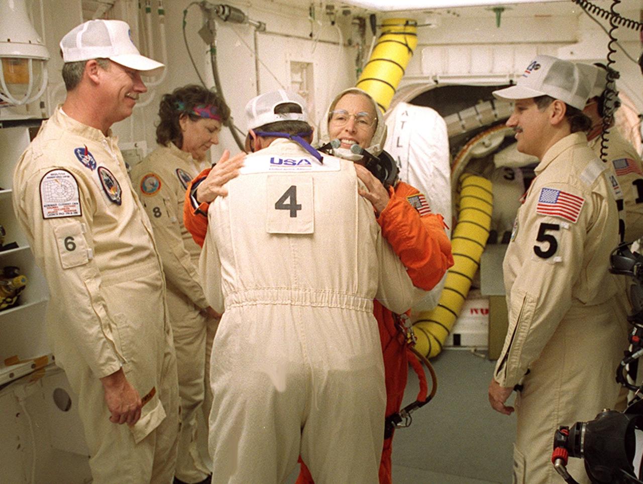 In the White Room before launch, STS-98 Mission Specialist Marsha Ivins gets a hug from a closeout crew member before she enters Space Shuttle Atlantis. The White Room is an environmentally controlled room at the end of the Orbiter Access Arm. Atlantis is carrying the U.S. Laboratory Destiny, a key module in the growth of the Space Station. Destiny will be attached to the Unity node on the Space Station using the Shuttle’s robotic arm. Three spacewalks are required to complete the planned construction work during the 11-day mission. This mission marks the seventh Shuttle flight to the Space Station, the 23rd flight of Atlantis and the 102nd flight overall in NASA’s Space Shuttle program. The planned landing is at KSC Feb. 18 about 1 p.m