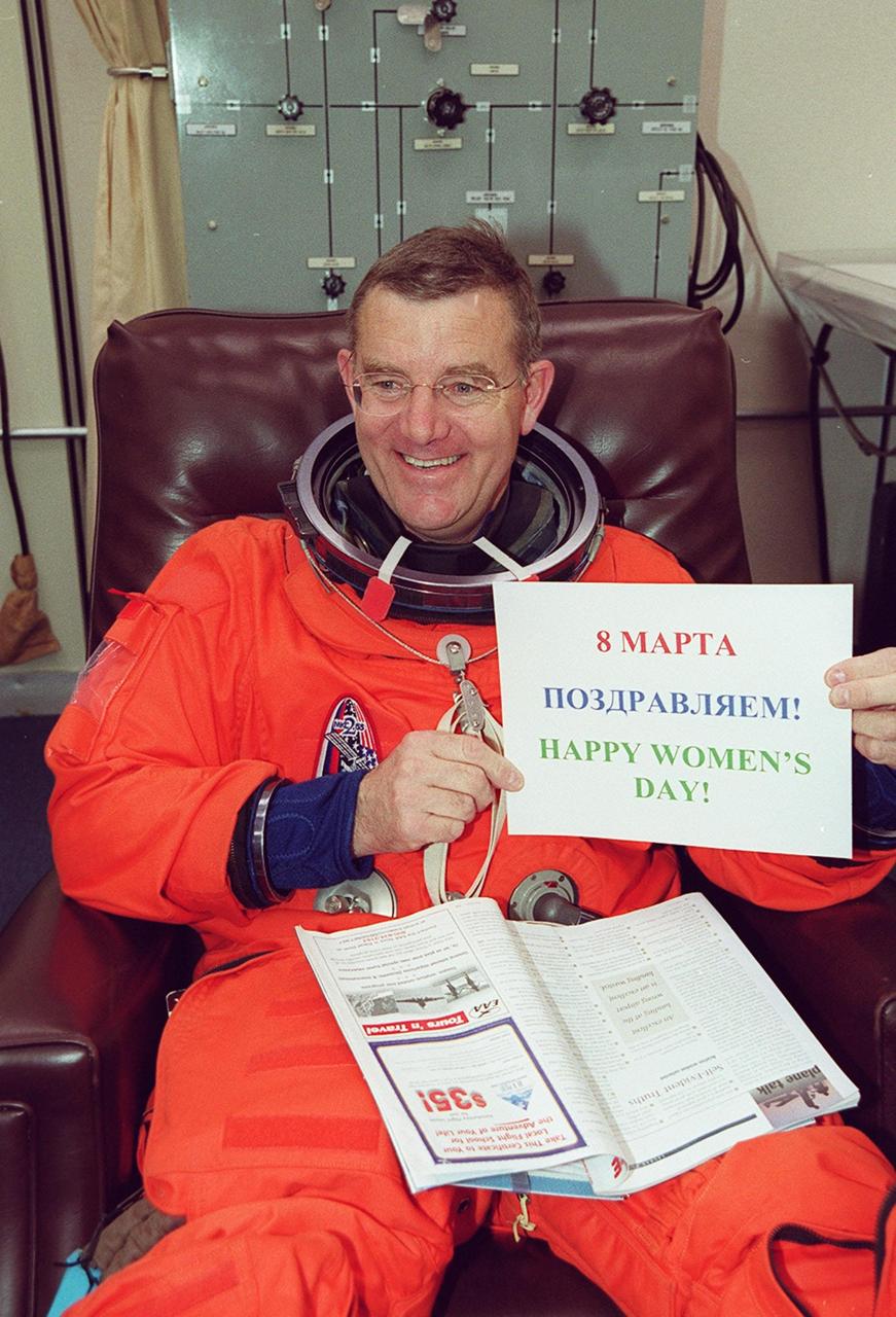 While suiting up in the Operations and Checkout Building, Mission Specialist James Voss shows his support of International Women’s Day, March 8, with a sign in both Cyrillic and English. Voss is also part of a crew, known as Expedition One, who will be replacing Expedition One on the International Space Station. STS-102 is the eighth construction flight to the Space Station, carrying the Multi-Purpose Logistics Module Leonardo. The primary delivery system used to resupply and return Station cargo requiring a pressurized environment, Leonardo will deliver up to 10 tons of laboratory racks filled with equipment, experiments and supplies for outfitting the newly installed U.S. Laboratory Destiny. Discovery is set to launch March 8 at 6:42 a.m. EST. The 12-day mission is expected to end with a landing at KSC on March 20