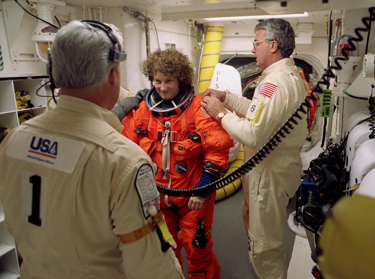 Technicians in the White Room, Launch Pad 39B, help STS-102 Mission Specialist Susan Helms with her launch and entry suit before she enters Space Shuttle Discovery. The mission is Helms’ fifth Shuttle flight. Helms is also part of the Expedition Two crew flying on the mission to replace the Expedition One crew on the Station. Discovery is carrying the Multi-Purpose Logistics Module Leonardo on the eighth construction flight to the International Space Station. The primary delivery system used to resupply and return Station cargo requiring a pressurized environment, Leonardo will deliver up to 10 tons of laboratory racks filled with equipment, experiments and supplies for outfitting the newly installed U.S. Laboratory Destiny. Discovery is set to launch March 8 at 6:42 a.m. EST. The 12-day mission is expected to end with a landing at KSC on March 20