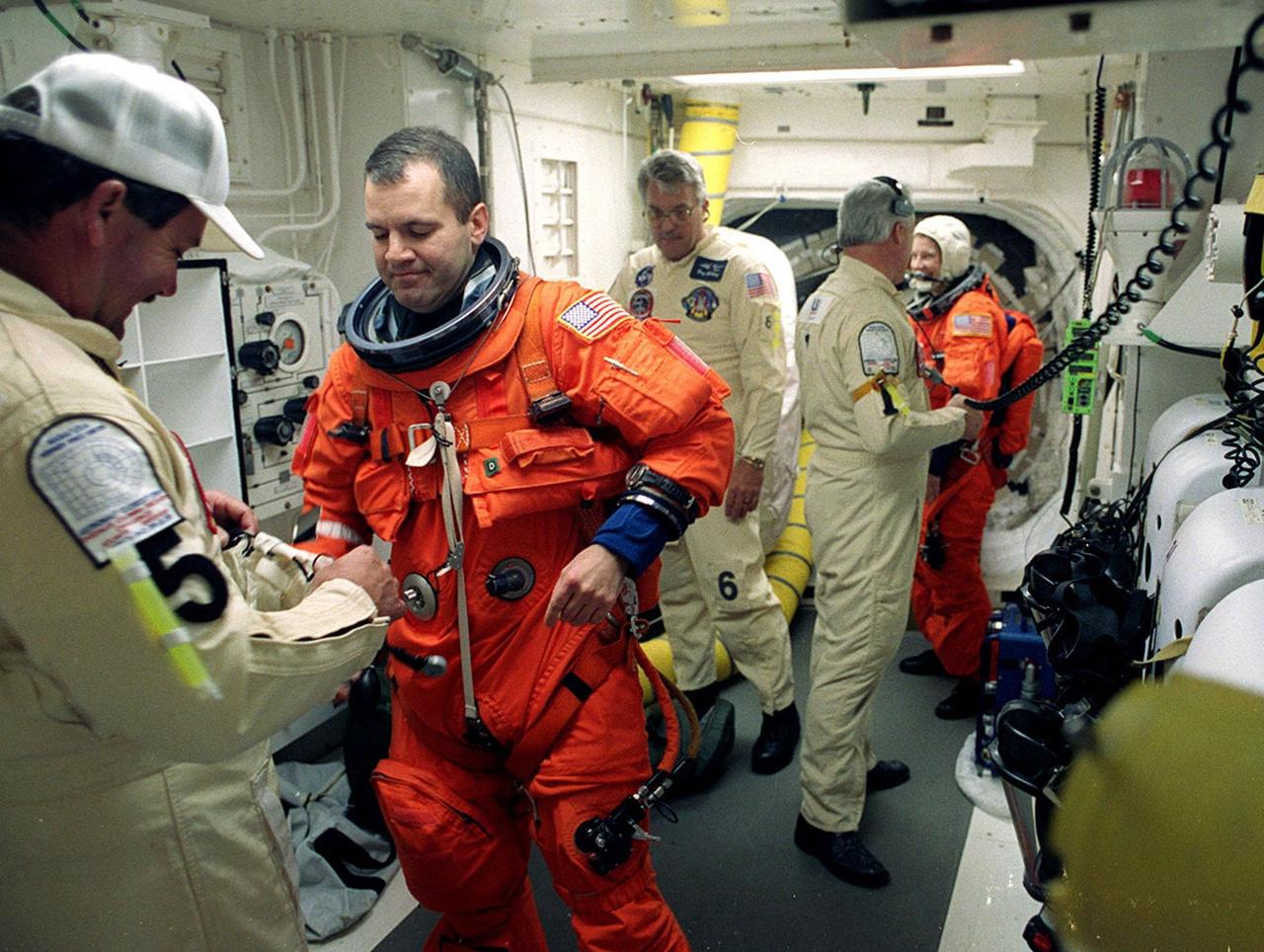 Technicians in the White Room, Launch Pad 39B, help STS-102 Mission Specialist Paul Richards with his launch and entry suit before he enters Space Shuttle Discovery. The mission is Richards’ first Shuttle flight. In the background is Mission Specialist Susan Helms. Discovery is carrying the Multi-Purpose Logistics Module Leonardo on the eighth construction flight to the International Space Station. The primary delivery system used to resupply and return Station cargo requiring a pressurized environment, Leonardo will deliver up to 10 tons of laboratory racks filled with equipment, experiments and supplies for outfitting the newly installed U.S. Laboratory Destiny. Discovery is set to launch March 8 at 6:42 a.m. EST. The 12-day mission is expected to end with a landing at KSC on March 20