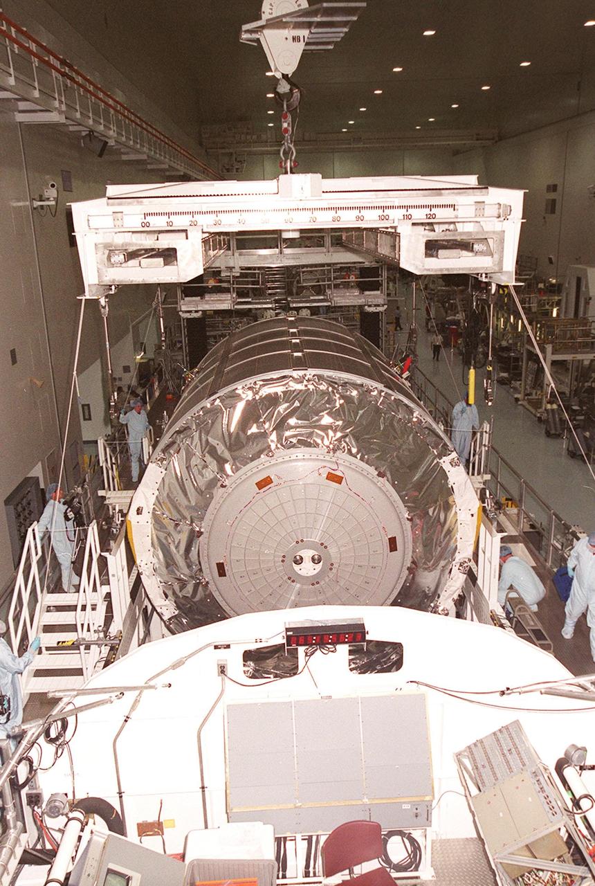 KENNEDY SPACE CENTER, FLA. -- In the Space Station Processing Facility, workers watch while an overhead crane lowers the Multi-Purpose Logistics Module Raffaello onto a weight and balance stand (foreground). Raffaello is the second MPLM built by the Italian Space Agency, and serves as a reusable logistics carrier and primary delivery system used to resupply and return station cargo requiring a pressurized environment. Weighing nearly 4.5 tons, the Raffaello measures 21 feet long and 15 feet in diameter. The MPLM will fly on mission STS-100, scheduled to launch aboard Space Shuttle Endeavour on April 19
