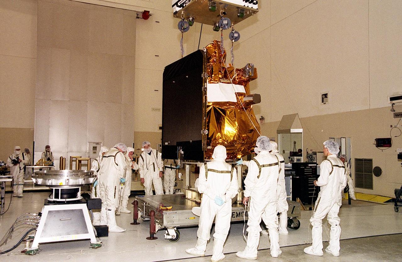The 2001 Mars Odyssey Orbiter, suspended by an overhead crane in the Space Assembly and Encapsulation Building 2, moves toward the spin table at left where it will be tested. The orbiter is being transferred to a spin table for testing. The orbiter carries three science instruments THEMIS, the Gamma Ray Spectrometer (GRS), and the Mars Radiation Environment Experiment (MARIE) that will map the mineralogy and morphology of the Martian surface, the elemental composition of the surface and determine the abundance of hydrogen in the shallow subsurface, and characterize aspects of the near-space radiation environment with regards to the radiation-related risk to human explorers. The Mars Odyssey Orbiter is scheduled for launch on April 7, 2001, aboard a Delta II rocket from Launch Pad 17-A, Cape Canaveral Air Force Station