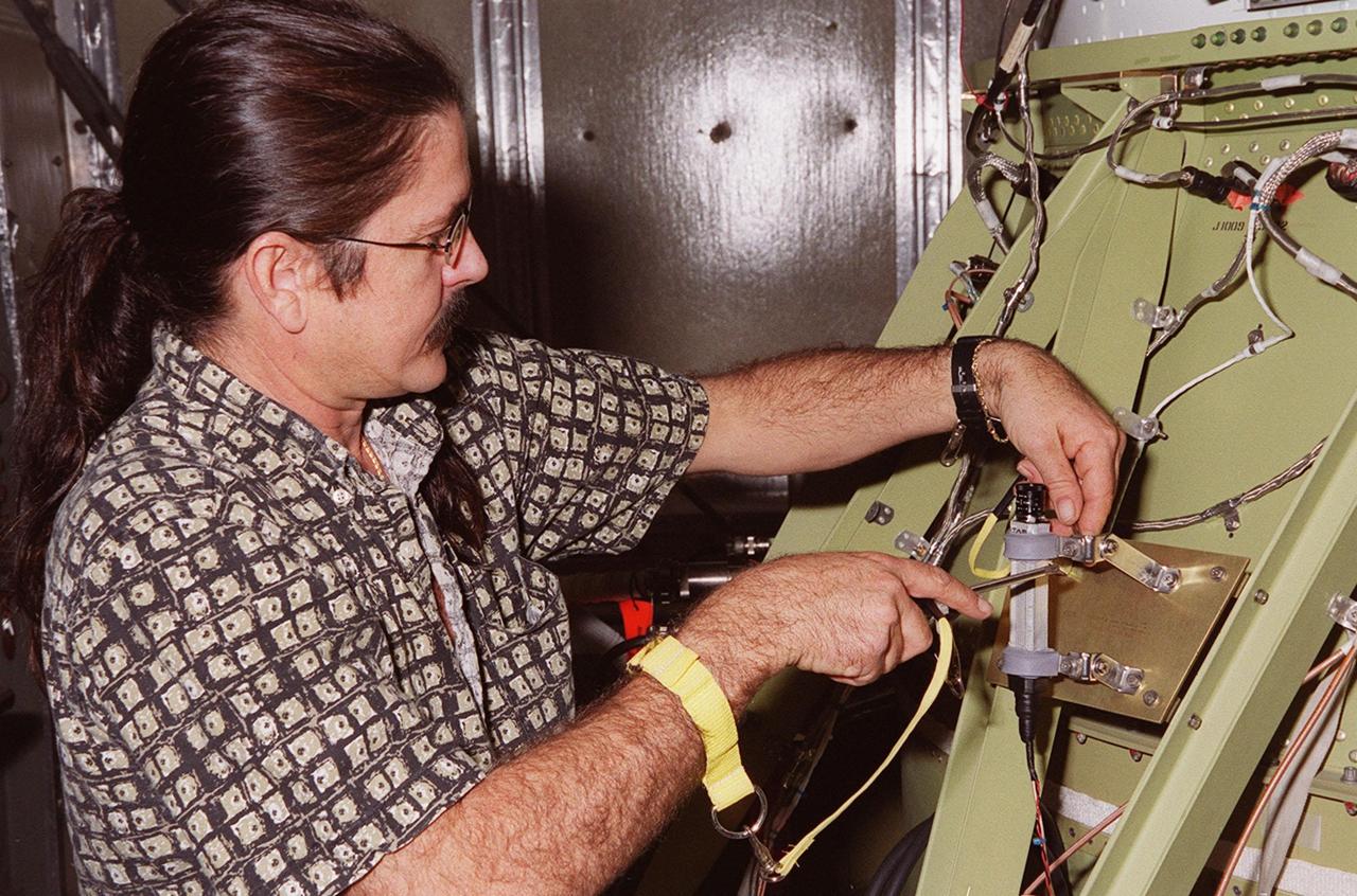 At Launch Pad 17-A, Cape Canaveral Air Force Station, a worker adjusts a bracket around the camera he is attaching to the second stage of the Delta II rocket for the Mars Odyssey launch. The orbiter carries three science instruments THEMIS, the Gamma Ray Spectrometer (GRS), and the Mars Radiation Environment Experiment (MARIE) that will map the mineralogy and morphology of the Martian surface. The Mars Odyssey Orbiter is scheduled for launch on April 7, 2001
