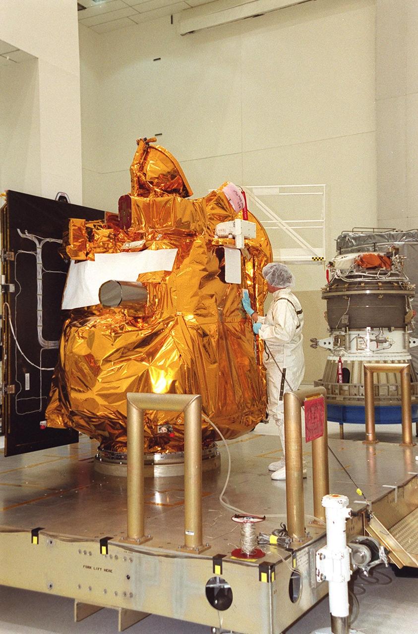 A worker in the Space Assembly and Encapsulation Facility 2 prepares the Mars Odyssey Orbiter (center) for its move to the third stage (right) of a Delta rocket. The Mars Odyssey is scheduled for launch on April 7, 2001, aboard a Delta II rocket from Launch Pad 17-A, Cape Canaveral Air Force Station