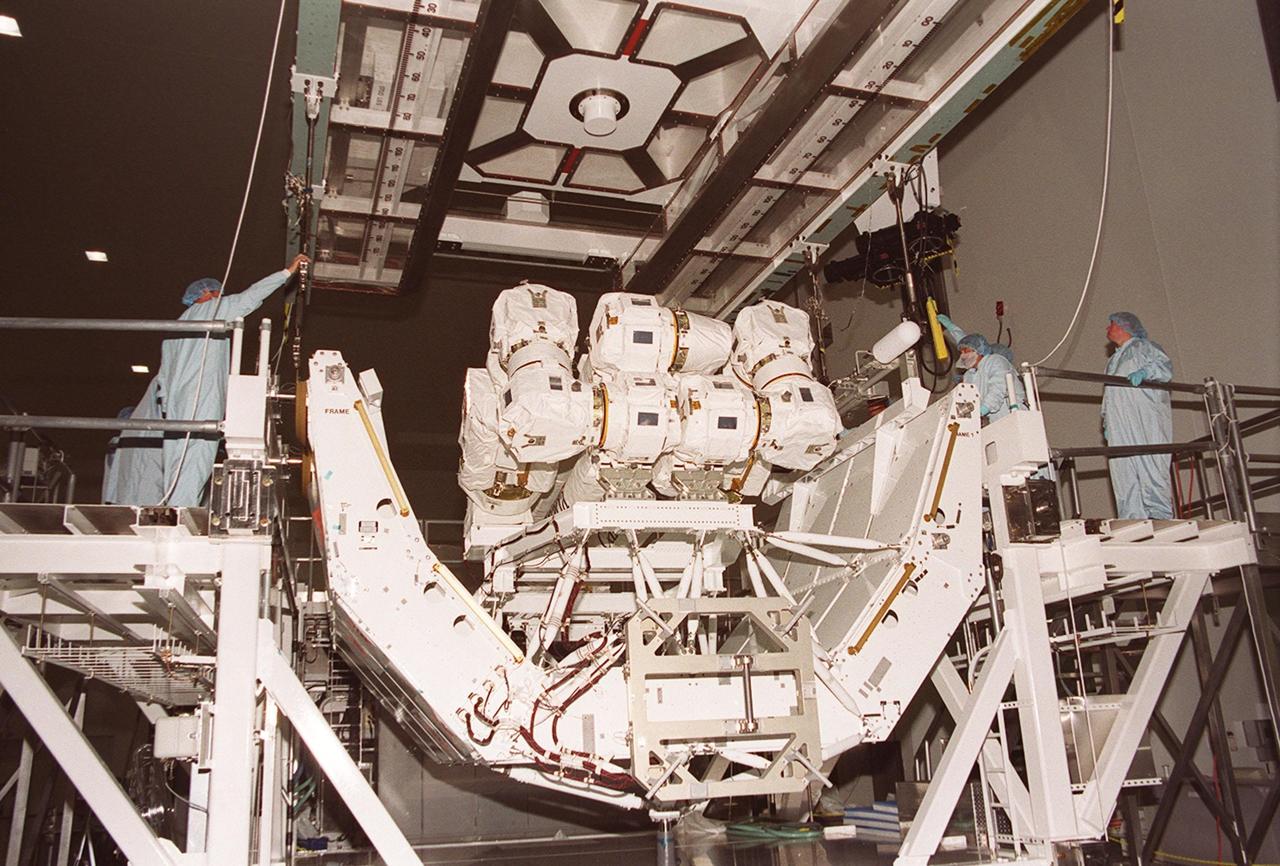 In the Space Station Processing Facility, an overhead crane moves into place over the Canadian robotic arm, SSRMS, and its pallet. The crane will lift the SSRMS and move it to the payload canister. The arm is 57.7 feet (17.6 meters) long when fully extended and has seven motorized joints. It is capable of handling large payloads and assisting with docking the Space Shuttle. The SSRMS is self-relocatable with a Latching End Effector, so it can be attached to complementary ports spread throughout the Station’s exterior surfaces. The SSRMS is part of the payload on mission STS-100, scheduled to launch April 19 at 2:41 p.m. EDT from Launch Pad 39A, KSC