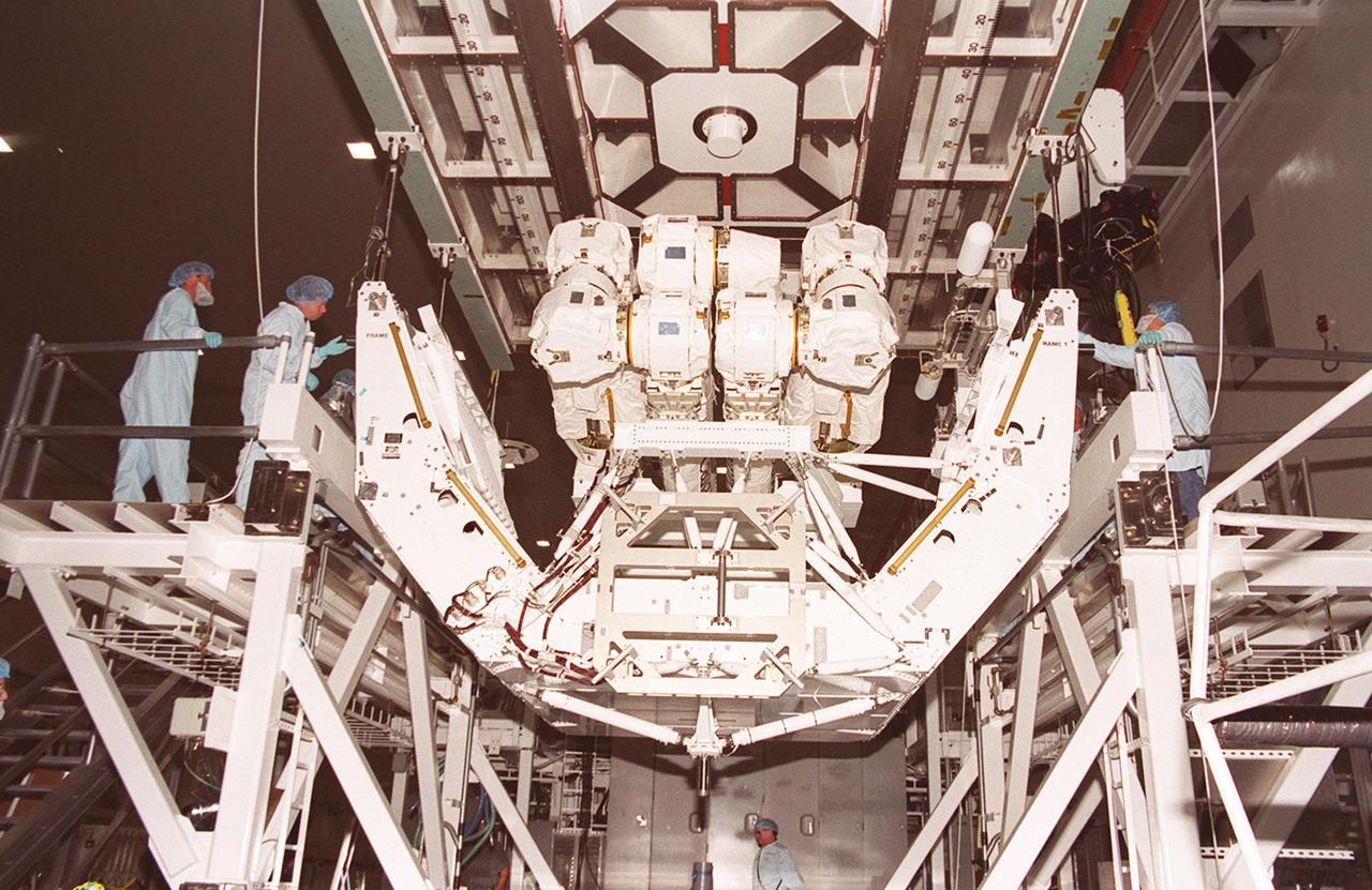 In the Space Station Processing Facility, an overhead crane lifts the pallet holding the Canadian robotic arm, SSRMS, to move it to the payload canister. The arm is 57.7 feet (17.6 meters) long when fully extended and has seven motorized joints. It is capable of handling large payloads and assisting with docking the Space Shuttle. The SSRMS is self-relocatable with a Latching End Effector, so it can be attached to complementary ports spread throughout the Station’s exterior surfaces. The SSRMS is part of the payload on mission STS-100, scheduled to launch April 19 at 2:41 p.m. EDT from Launch Pad 39A, KSC