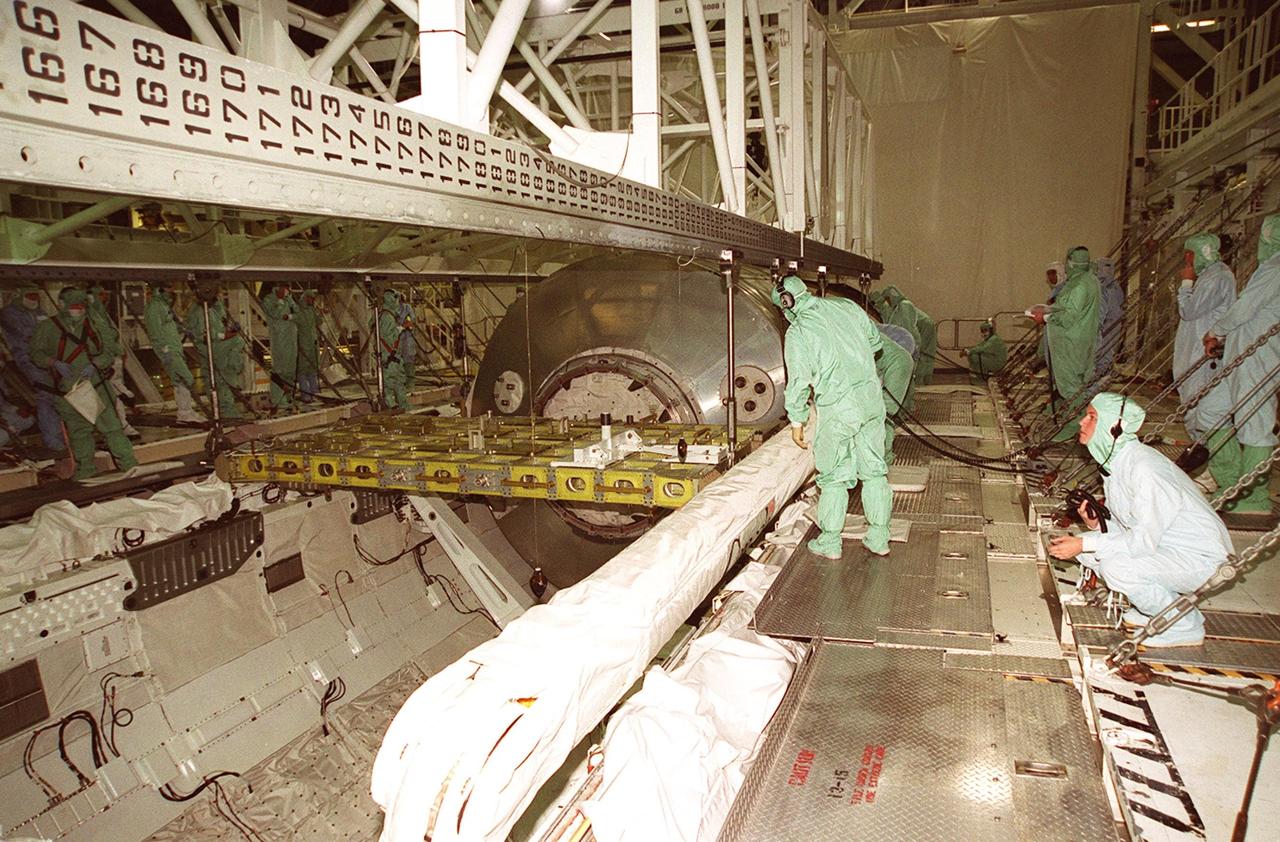 KENNEDY SPACE CENTER, FLA. -- Workers in the Orbiter Processing Facility bay 2 check the attachments on the overhead crane to the Multi-Purpose Logistics Module Leonardo and the integrated cargo carrier behind it sitting in Discovery’s payload bay. The MPLM has just returned from its first round trip to the International Space Station on mission STS-102. Attached to the length of the payload bay, in front of Leonardo, is the robotic arm that was used to remove and position Leonardo on the ISS. Leonardo will be lifted from the payload bay and transferred to the SSPF to prepare it for future missions. The MPLM serves as a cargo van, carrying equipment and supplies to the Space Station