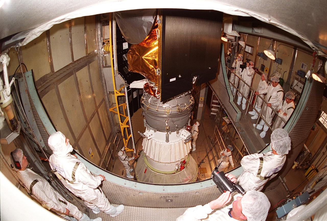 Workers at Launch Complex 17-A, Cape Canaveral Air Force Station, watch as a piece of the Delta rocket fairing is moved into place around the Mars Odyssey spacecraft. NASA’s latest explorer carries three scientific instruments to map the chemical and mineralogical makeup of Mars: a thermal-emission imaging system, a gamma ray spectrometer and a Martian radiation environment experiment. The imaging system will map the planet with high-resolution thermal images and give scientists an increased level of detail to help them understand how the mineralogy of the planet relates to the land forms. In addition, Odyssey will serve as a communications relay for U.S. and international landers arriving at Mars in 2003/2004. The Mars Odyssey is scheduled for launch aboard a Delta II rocket April 7, 2001, at 11:02 a.m. EST