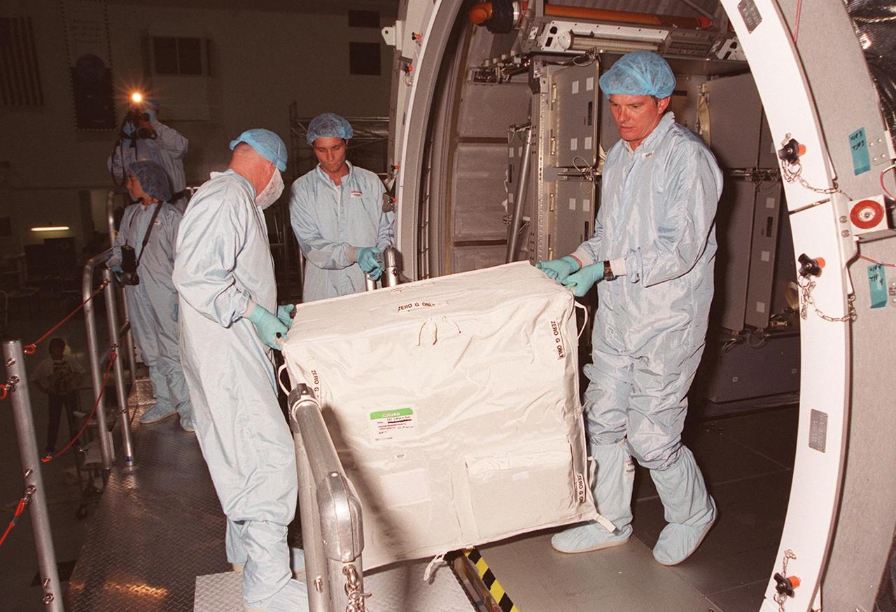 KENNEDY SPACE CENTER, FLA. -- Inside the Multi-Purpose Logistics Module Leonardo, which is in the Space Station Processing Facility, workers remove one of the containers returned from the International Space Station on mission STS-102. The MPLM brought back to KSC nearly a ton of trash and excess equipment from the Space Station. Leonardo is one of three MPLMs built by the Italian Space Agency to serve as “cargo vans” to the Station, carrying supplies and equipment. In the SSPF, Leonardo will be prepared for a future mission